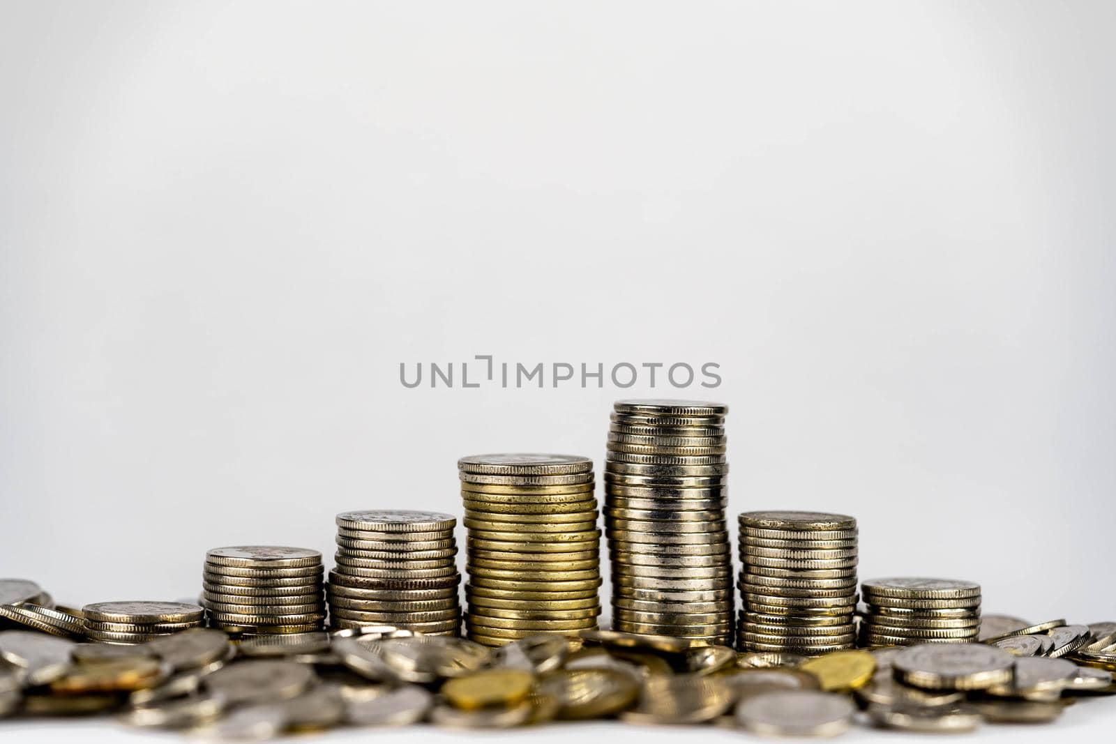 Seven stacks of golden coins with different heights arranged in growing direction, isolated on white background by billroque