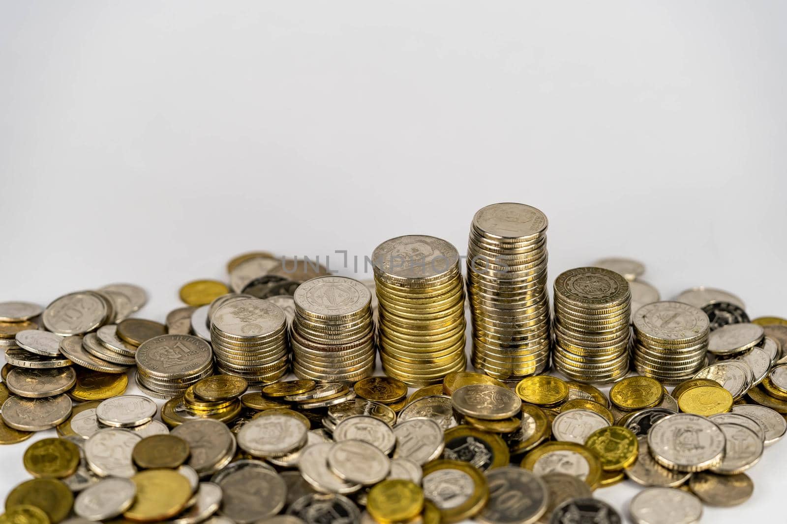Seven stacks of golden coins with different heights arranged in growing direction, isolated on white background. Coins scattered