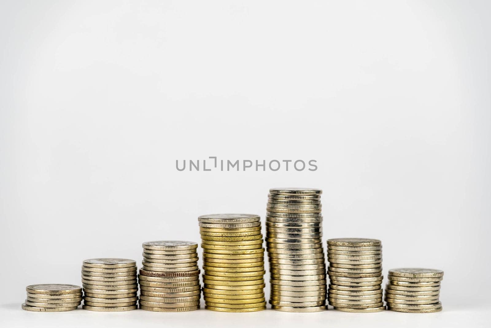 Seven stacks of golden coins with different heights arranged in growing direction, isolated on white background by billroque