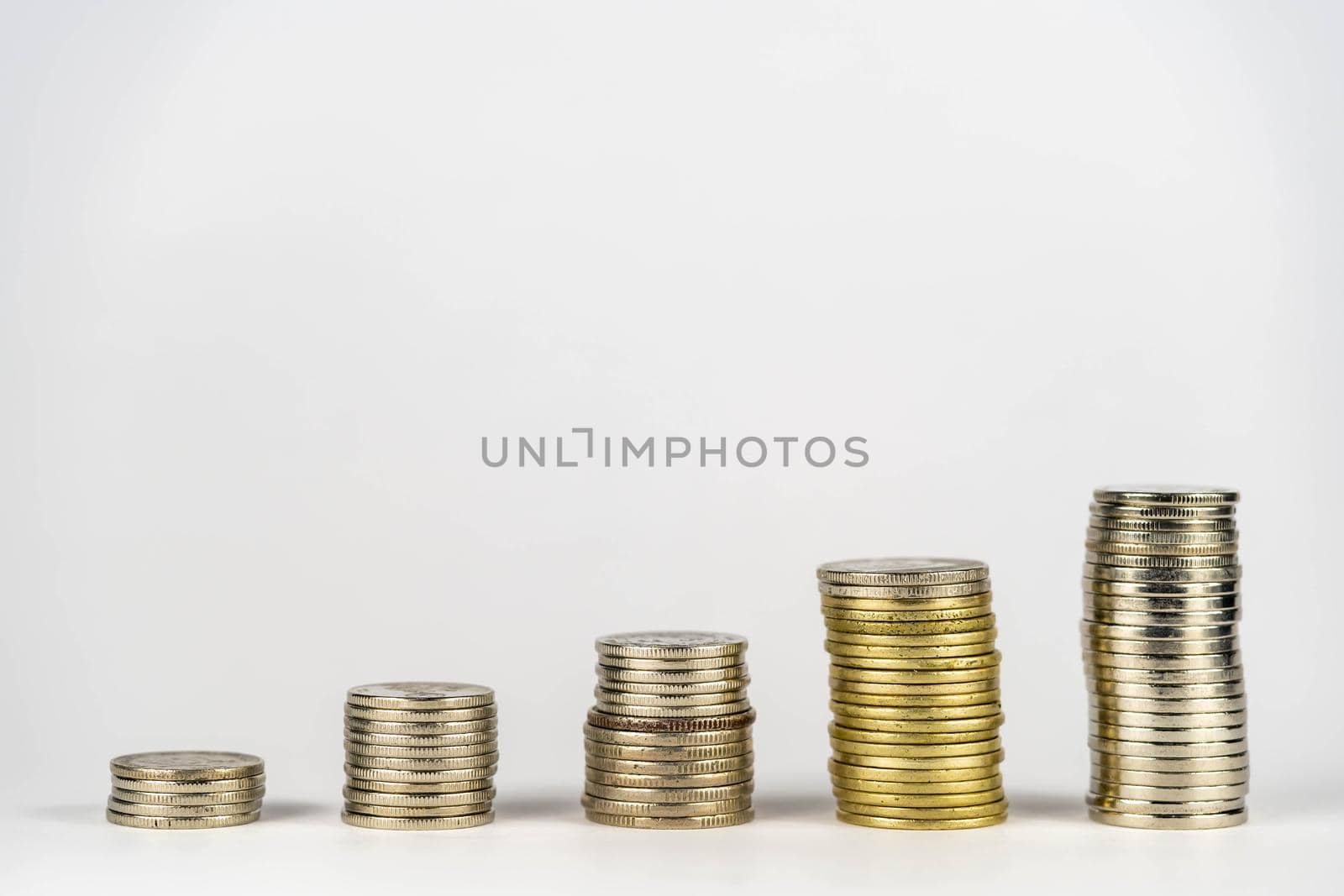 Five stacks of golden coins with different heights arranged in growing direction, isolated on white background