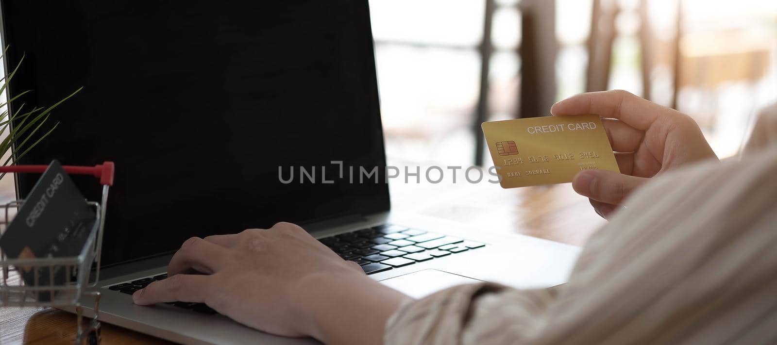 Man hand holding credit card and using laptop at home, Businessman or entrepreneur working, Online shopping, e-commerce, internet banking, spending money, working from home concept.