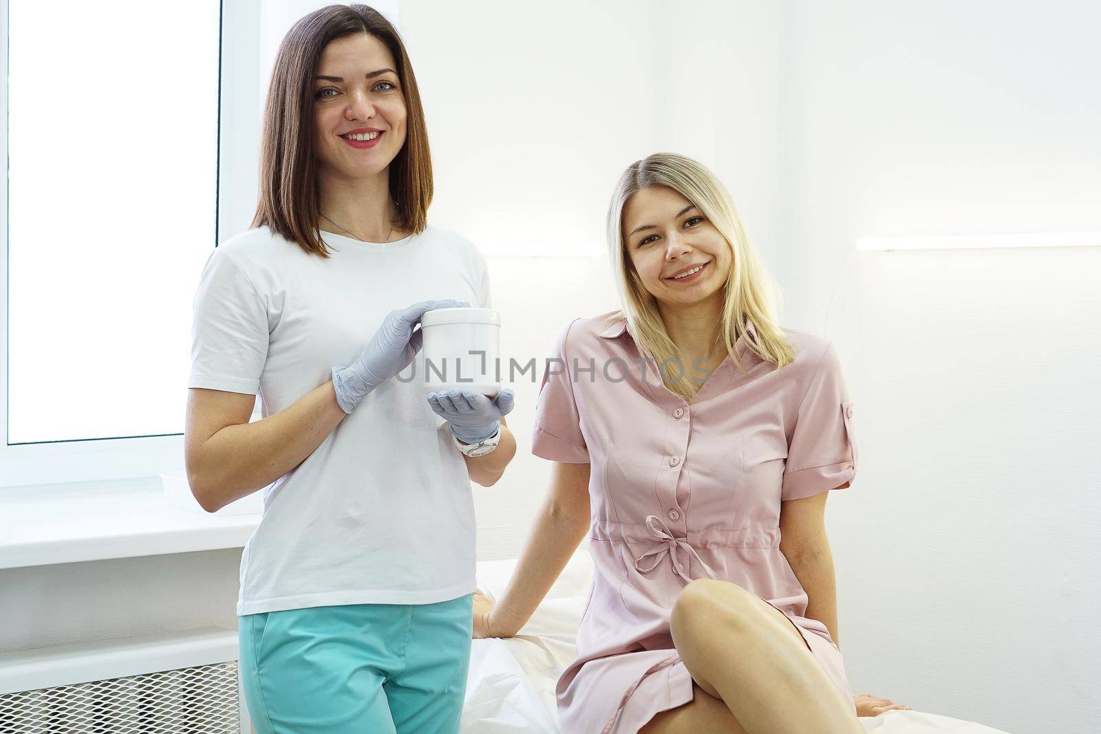 Doctor shows the patient remedy in beauty salon. Cosmetology the doctor advises the patient