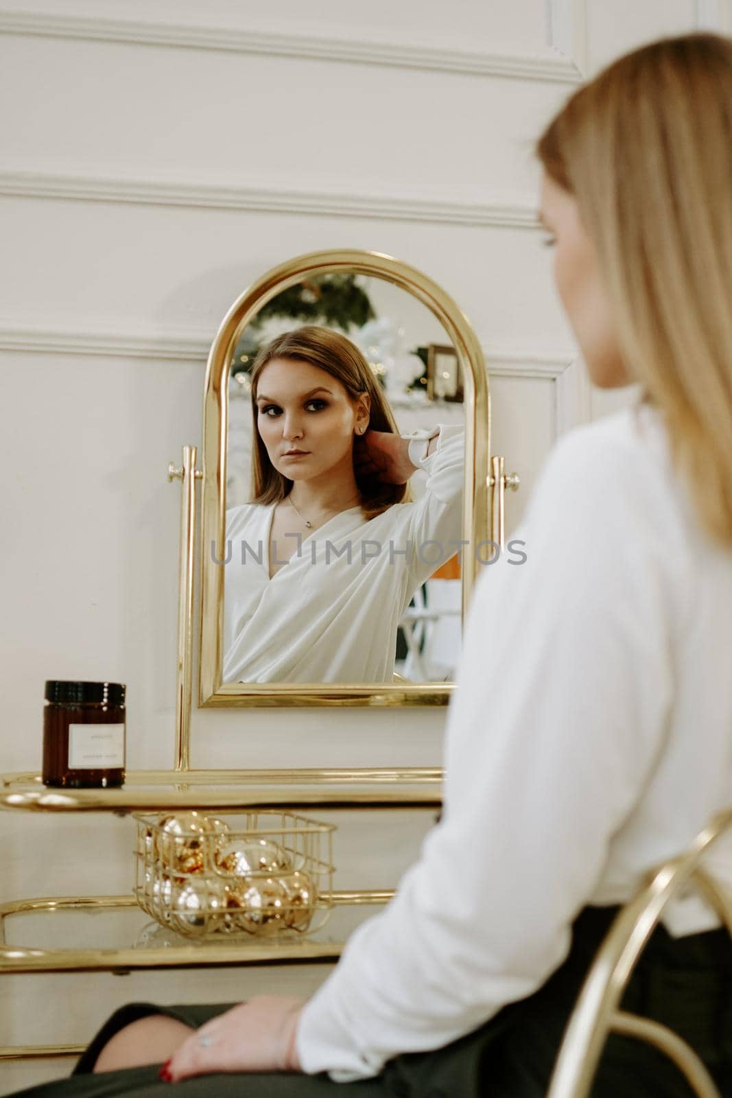 Beautiful woman in a strict white blouse in her room near her dressing table