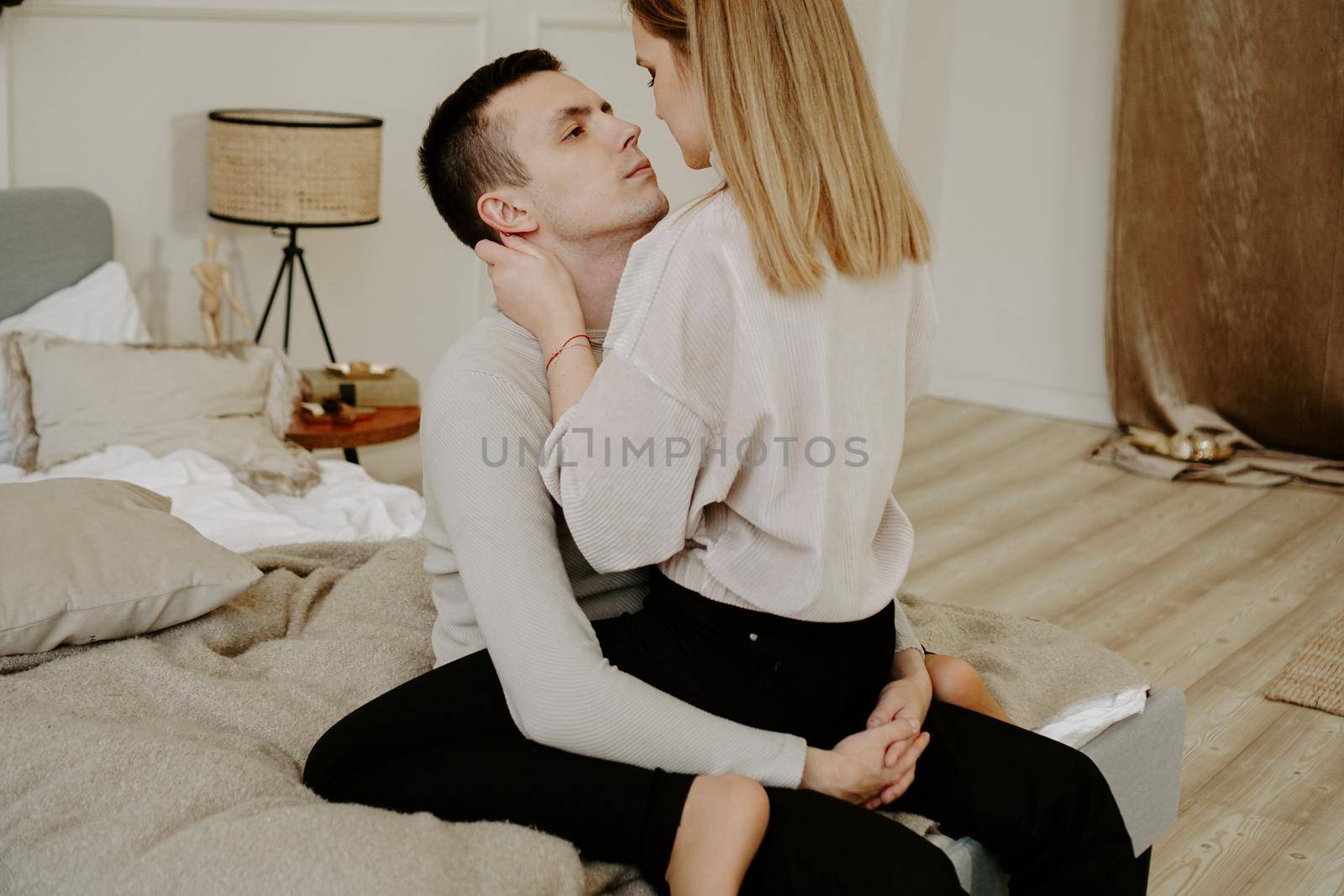 Close-up portrait of a beautiful young couple hugs in bed at home. Soft colors