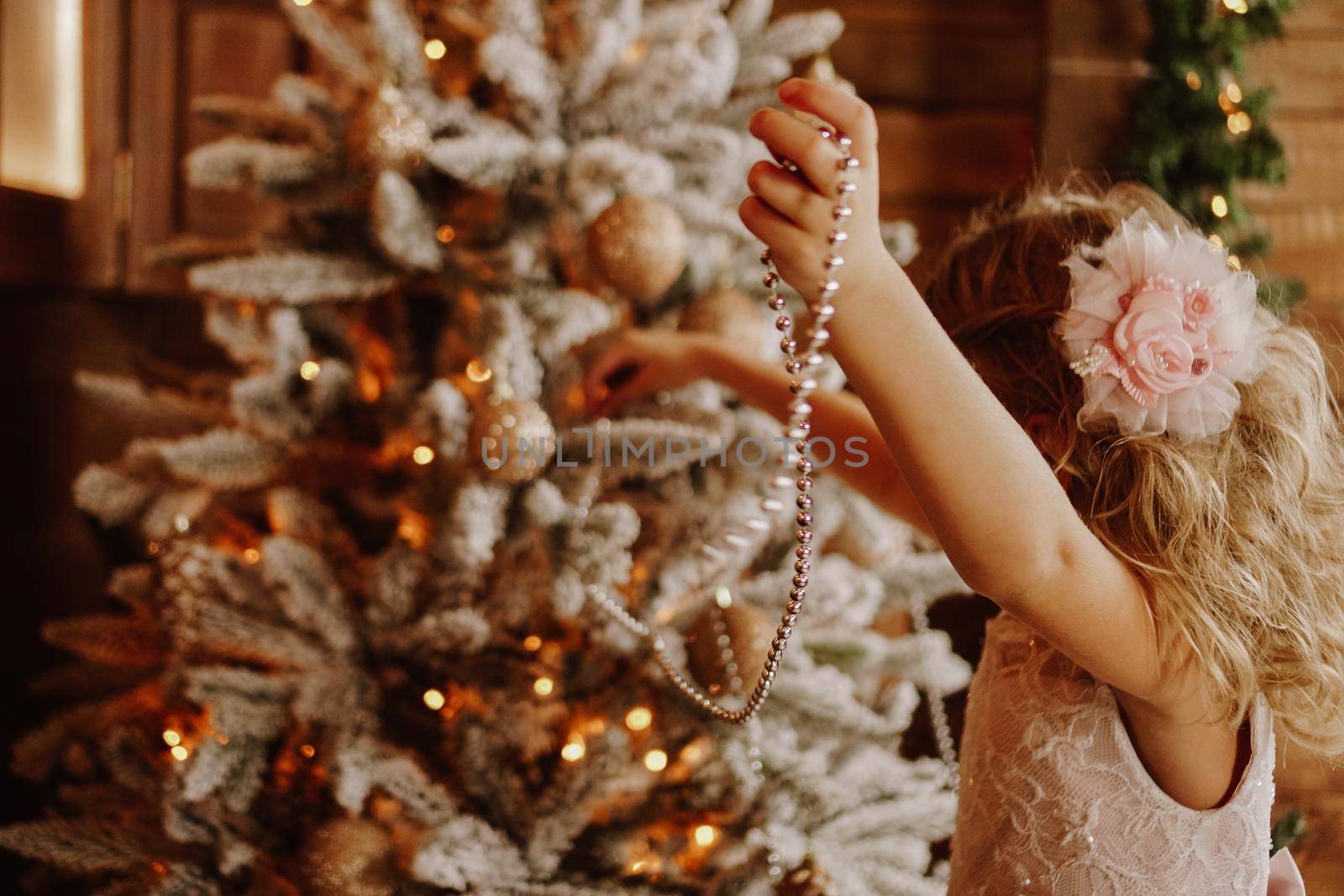 Girl decorates the christmas tree with beads by natali_brill