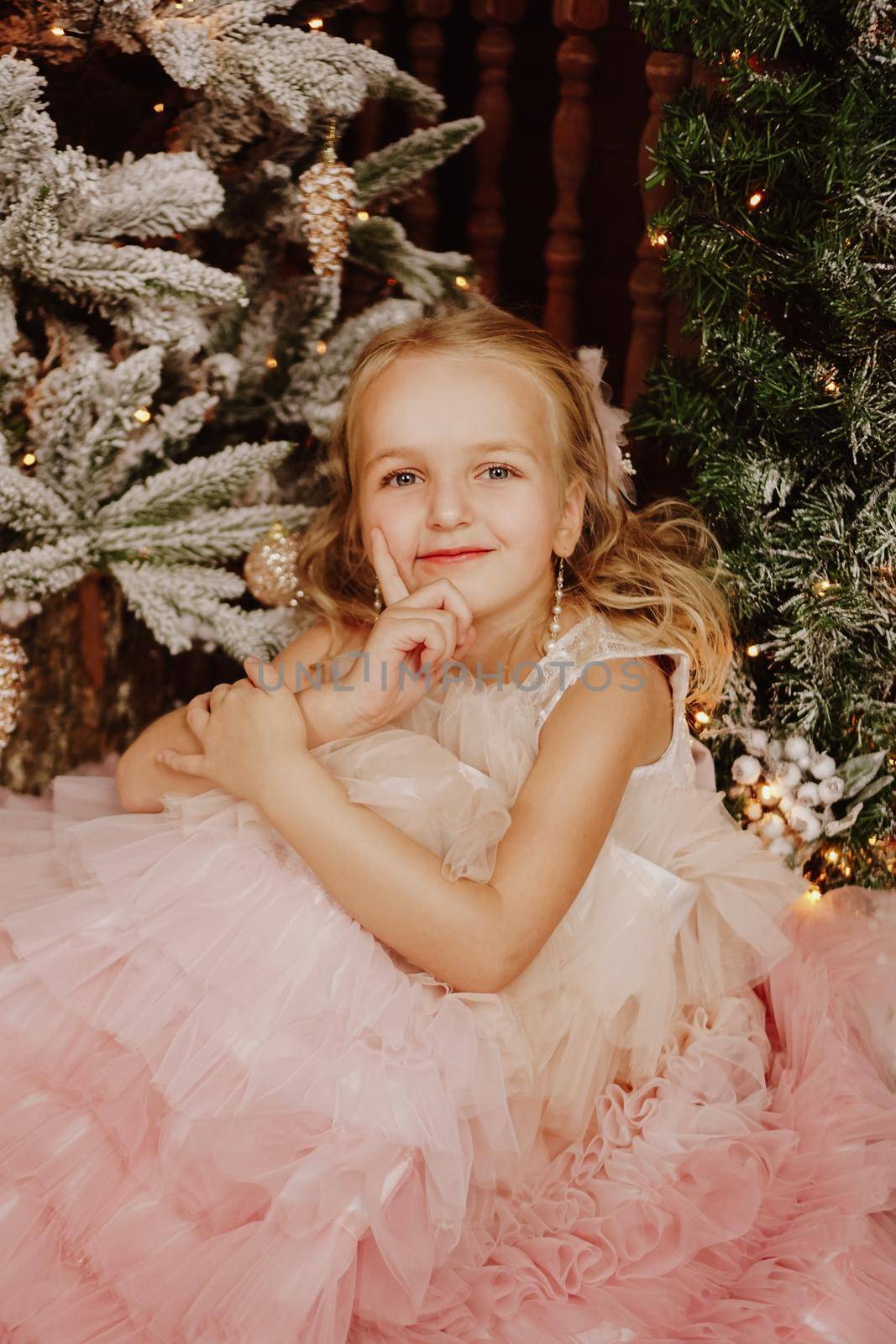 Happy Girl in a pink dress near the Christmas tree