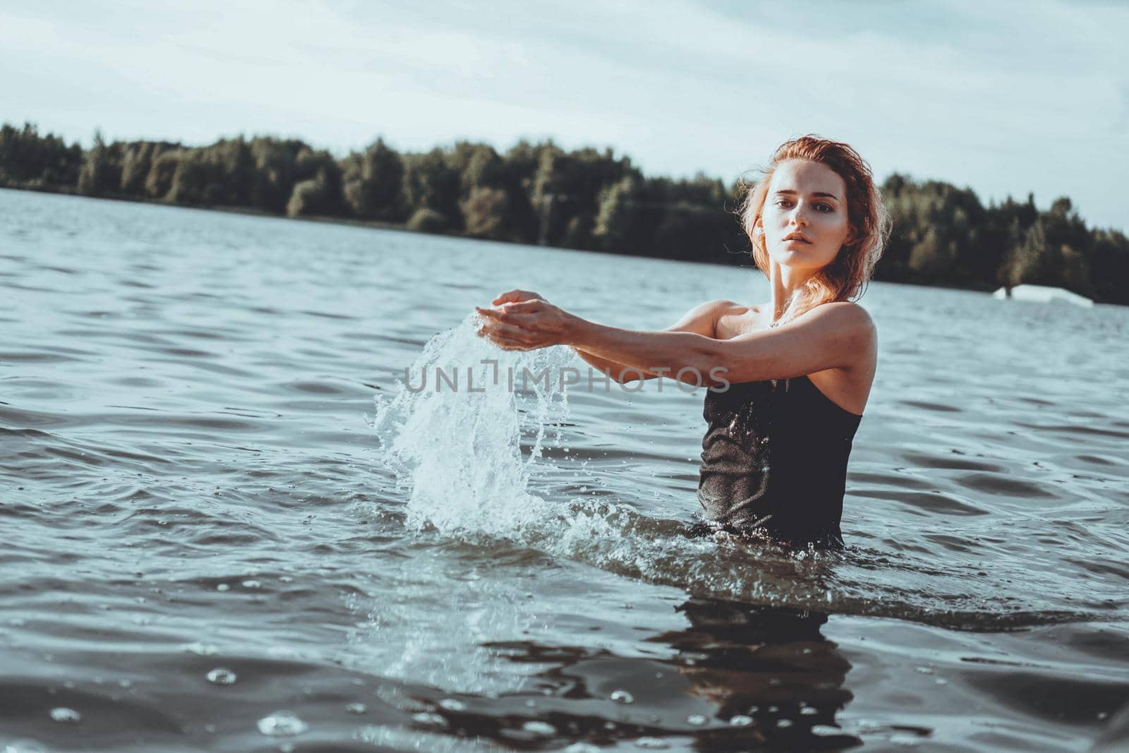 Young beautiful woman standing in the water. Black swimsuit. Vintage style