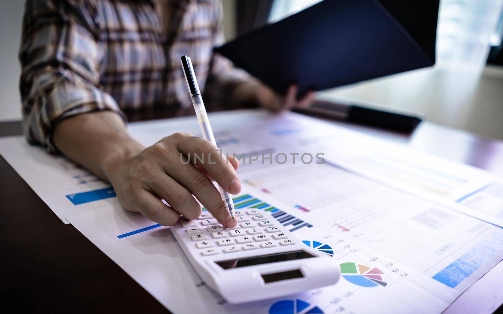 Finance and Accounting concept. Close up Businessman using calculator for do math finance and reading document from business document folder. by pravinrus