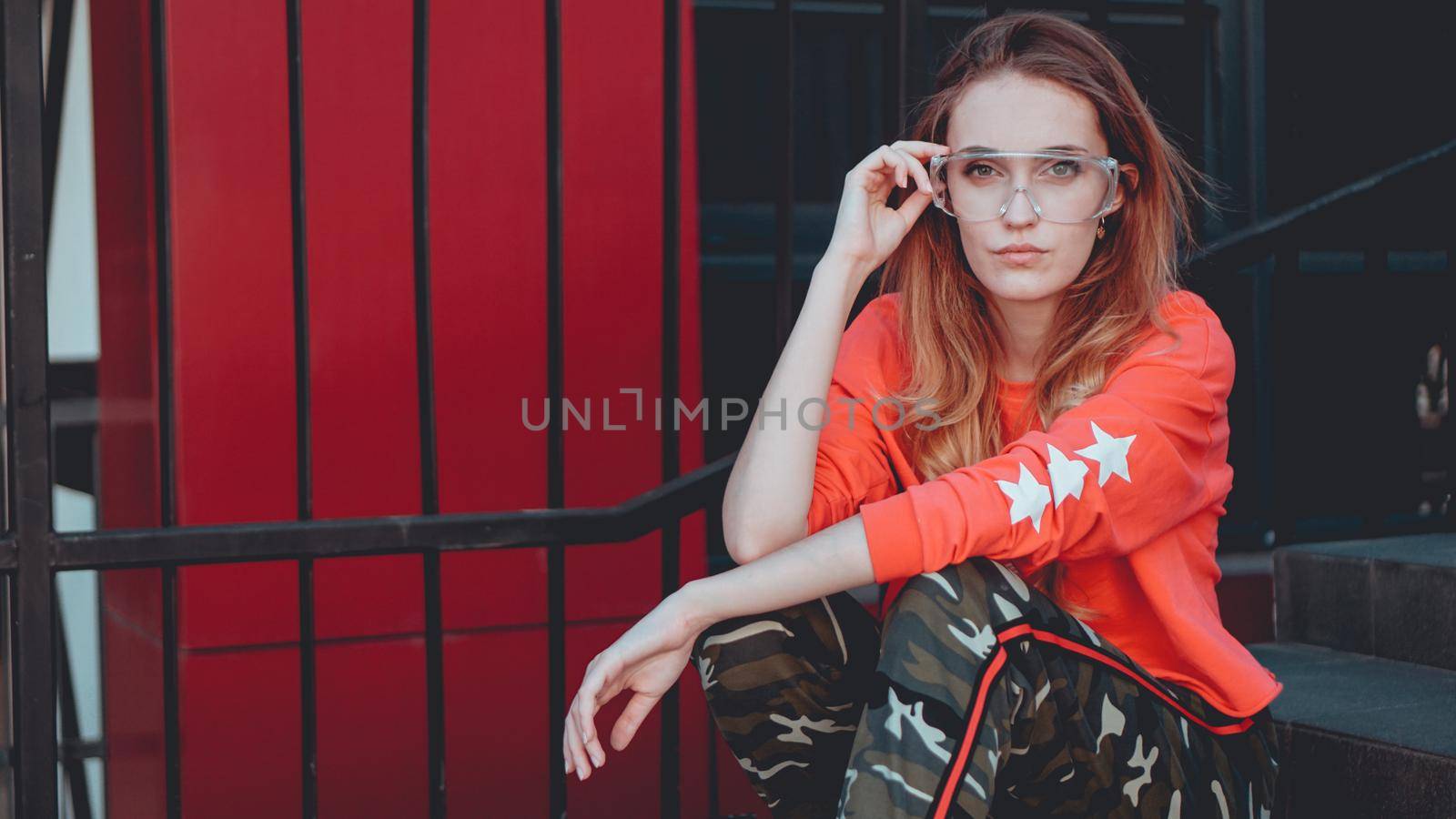 Fashion model wearing red hoodie with inscription los angeles posing at parking by natali_brill