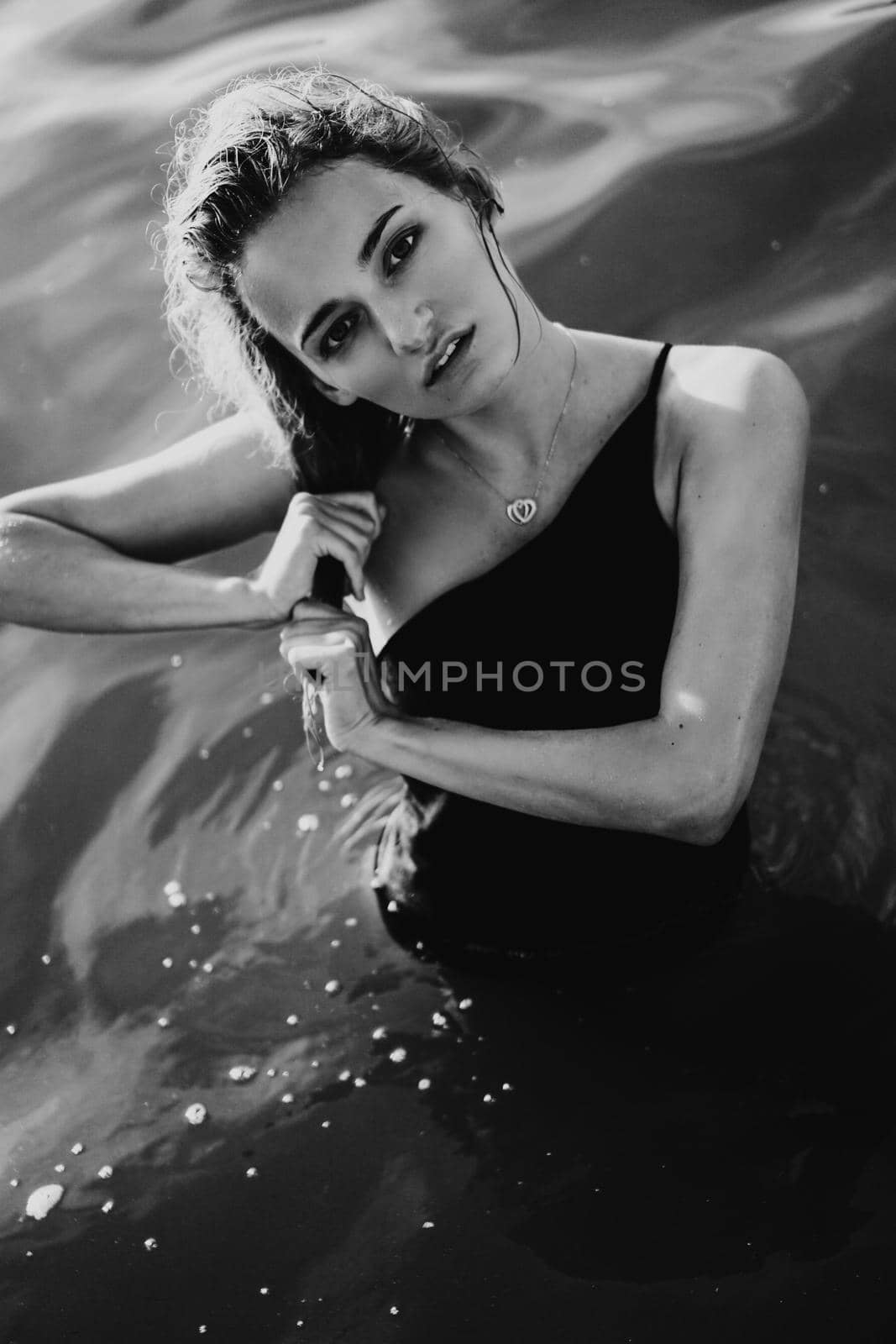 Young beautiful woman standing in the water. Black swimsuit. Vintage style. vertical photo. Black and white