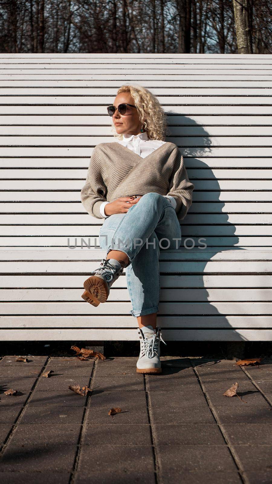 Pretty woman in sunglasses on bench at autumn park alone, lifestyle people concept