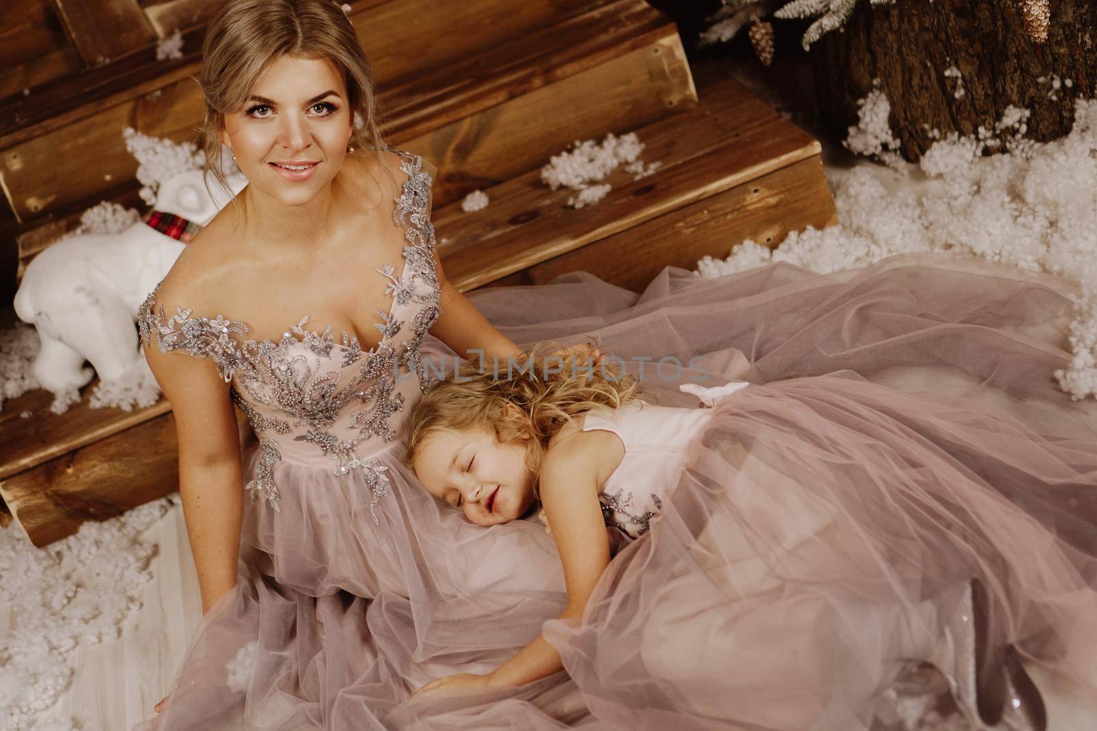 Mother and her daughter in pink dresses near the Christmas decorations by natali_brill
