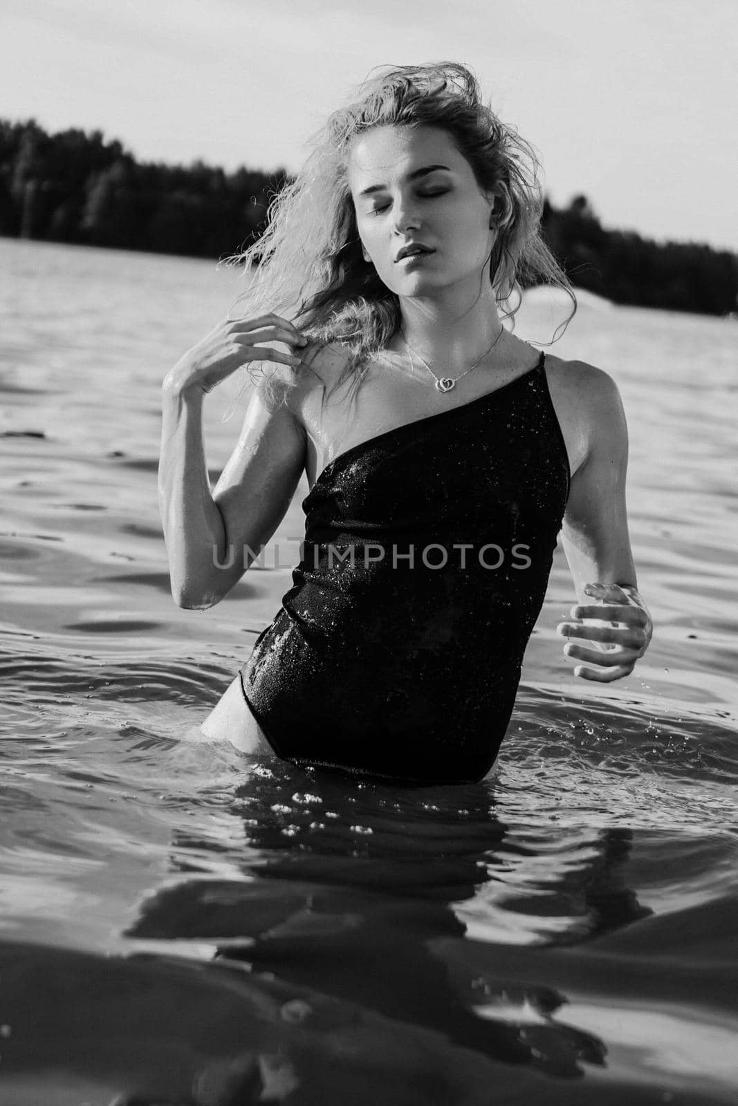 Young beautiful woman standing in the water. Black swimsuit. Vintage style. vertical photo. Black and white