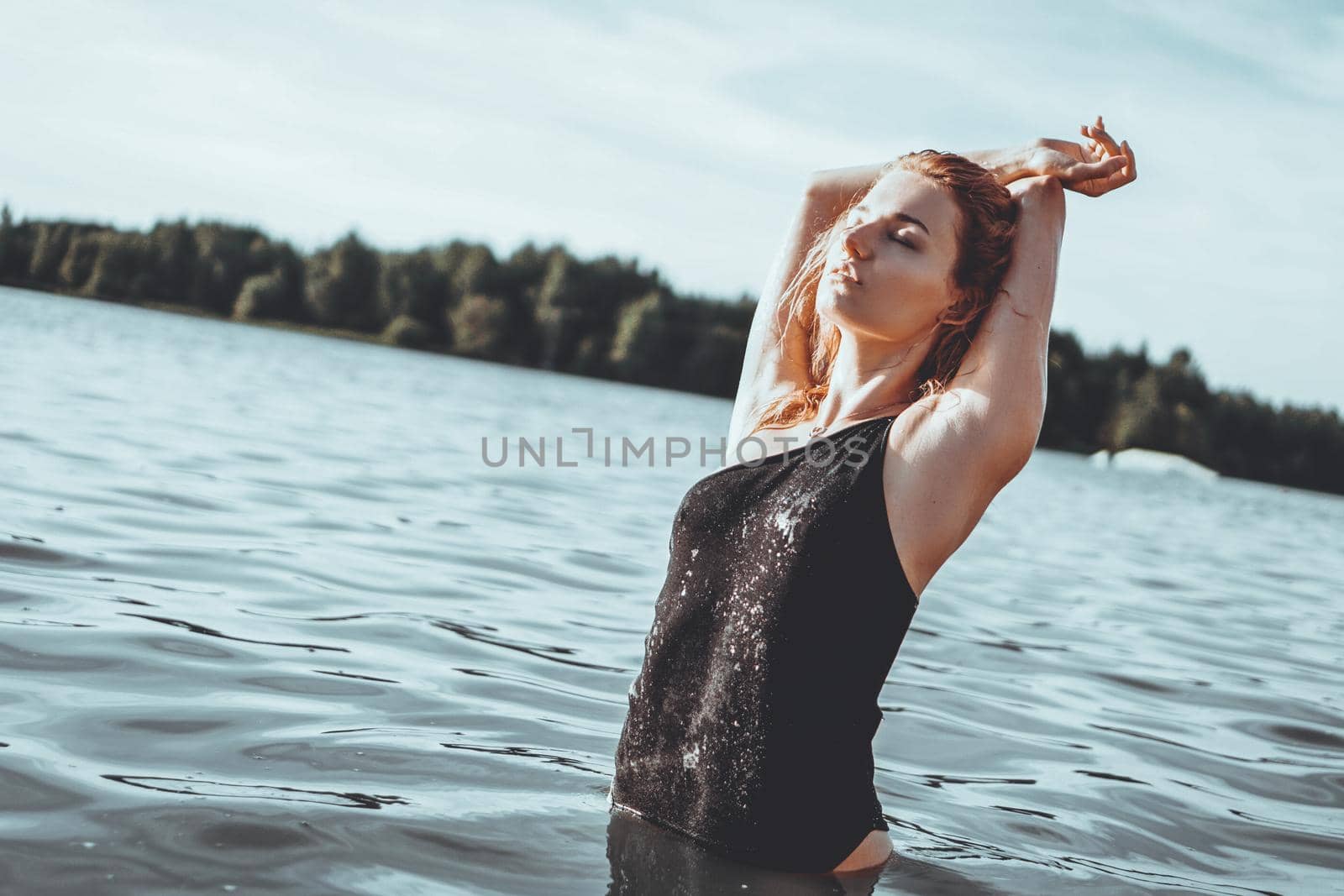 Young beautiful woman standing in the water. Black swimsuit. Vintage style