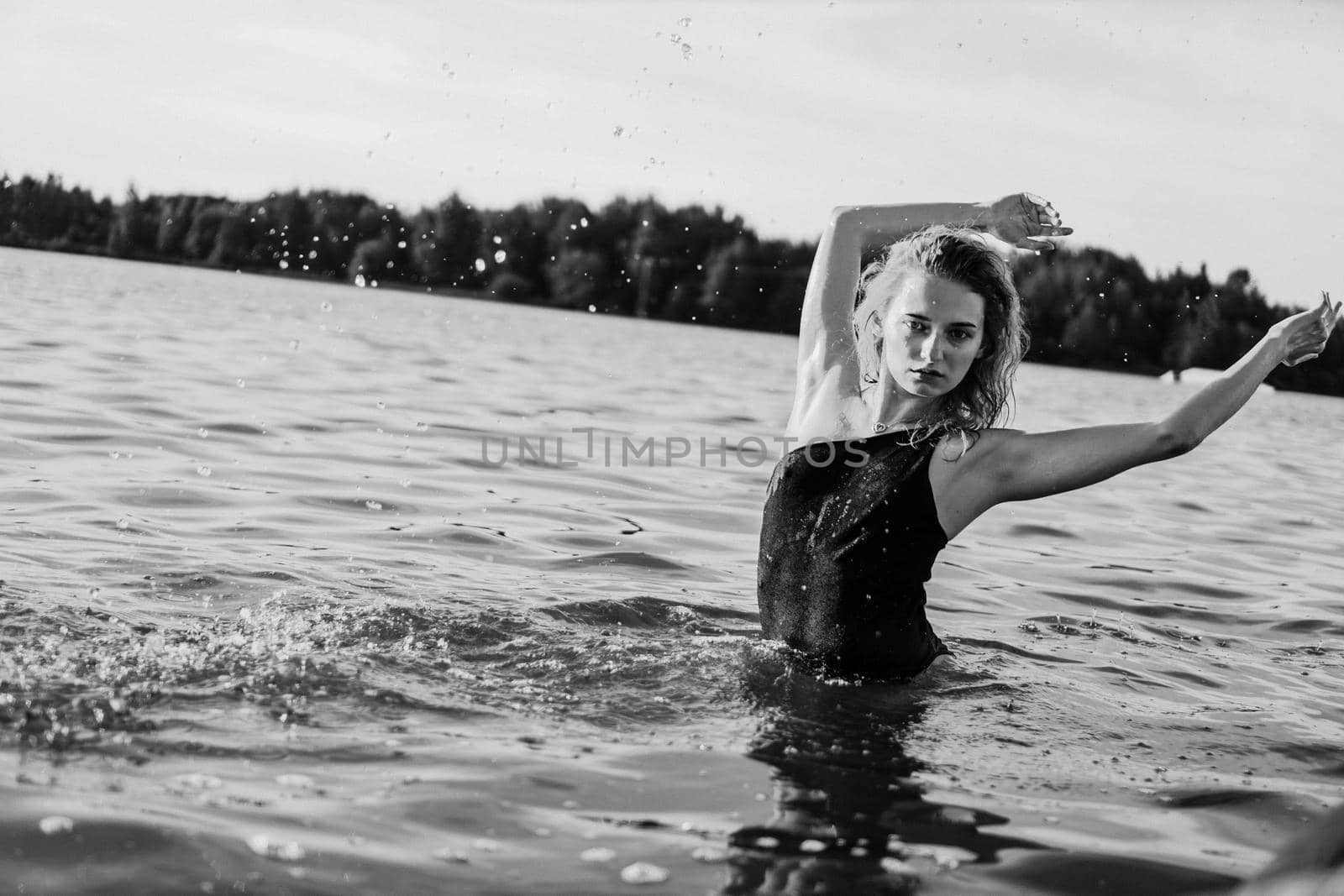 Young beautiful woman standing in the water. Black swimsuit. Vintage style. Black and white