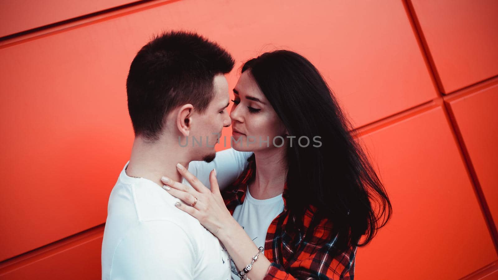 Couple kissing against isolated red wall in the city by natali_brill