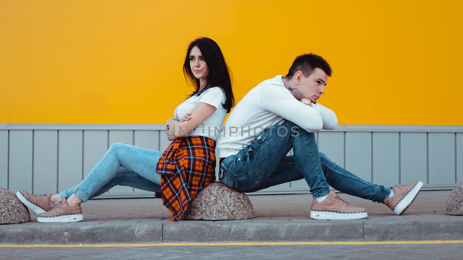 Confused young couple standing with one anothers back over yellow background by natali_brill