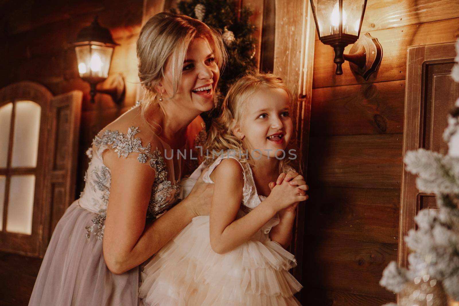 Young beautiful mother holds a little daughter who decorates a Christmas tree in the fairy room