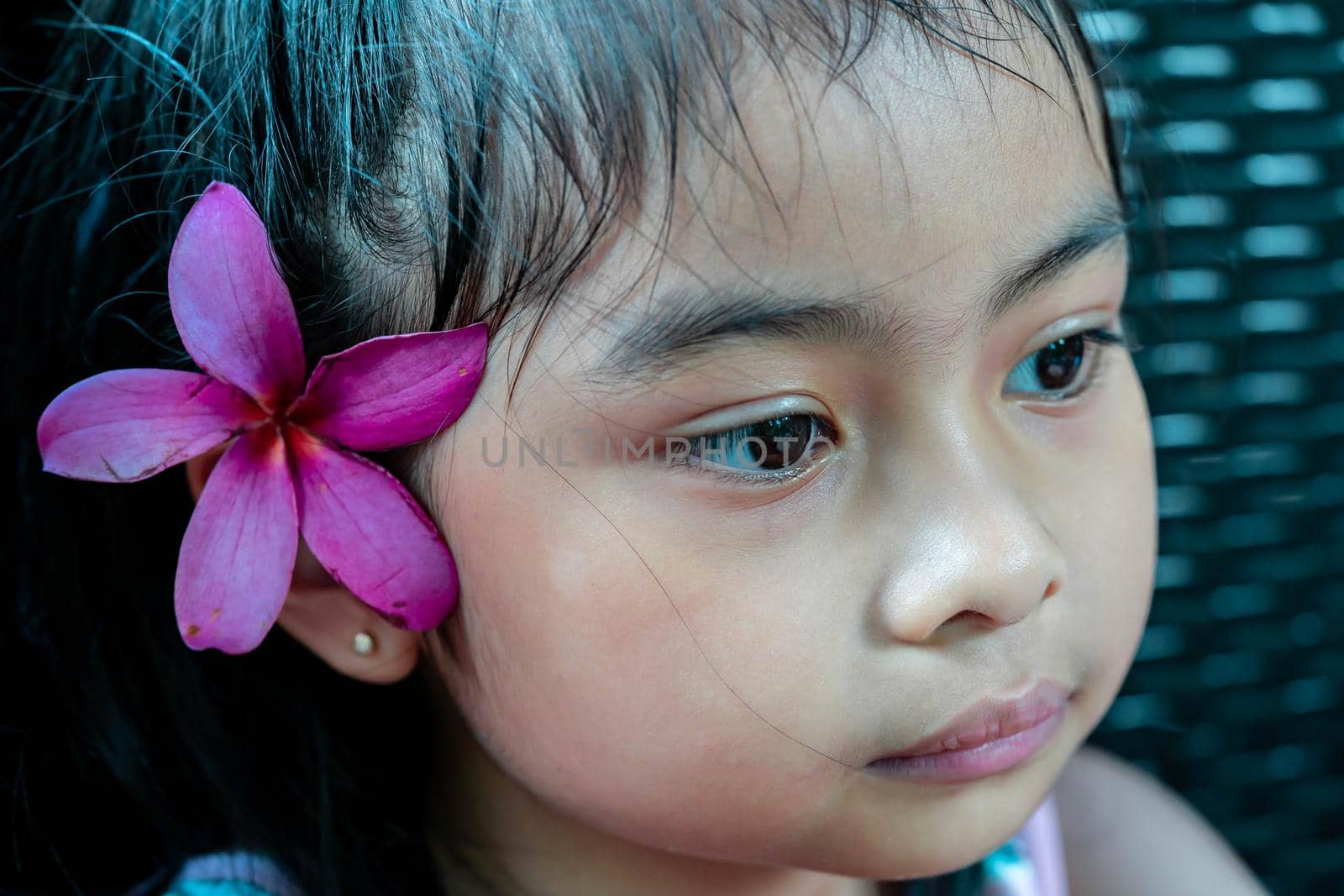 Little girl with large pink flower behind ear. Pretty asian child portrait with flower behind ear by billroque