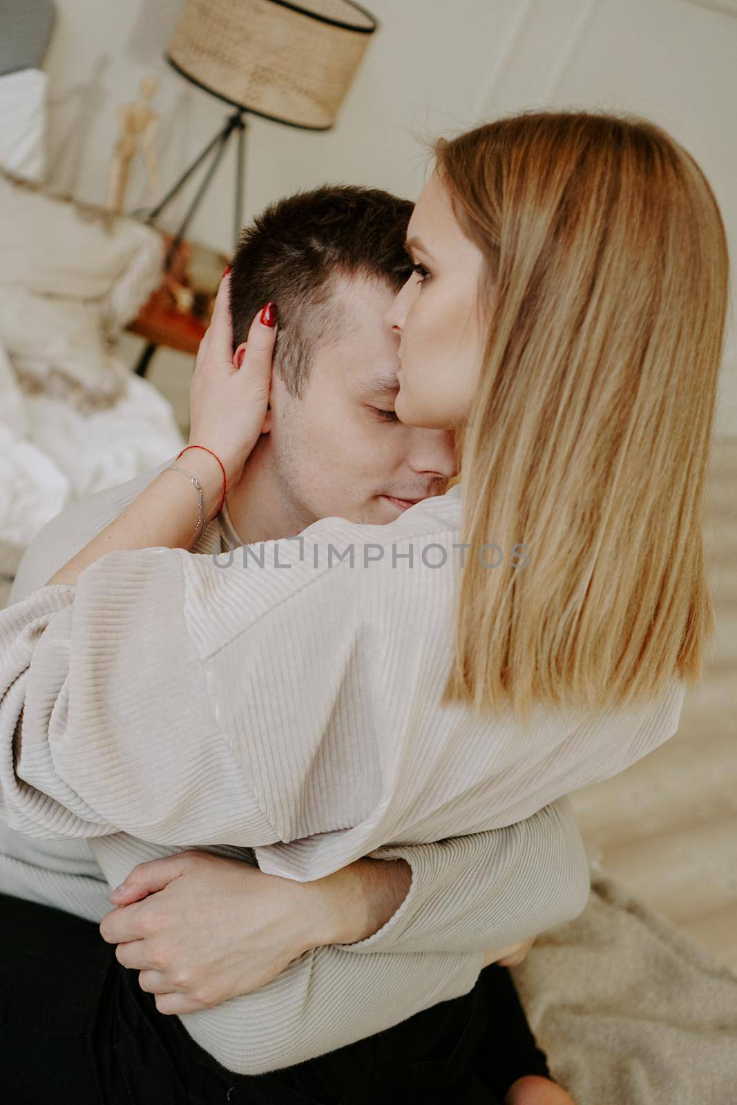 Close-up portrait of a beautiful young couple hugs in bed at home. Soft colors