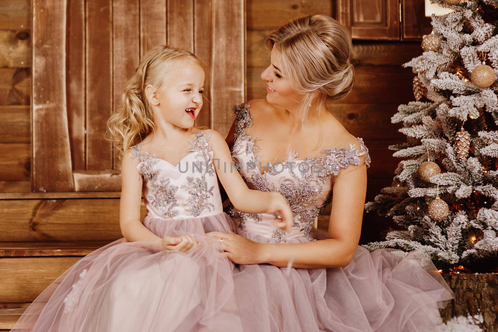 Happy Mother and her daughter in pink dresses near the Christmas decorations