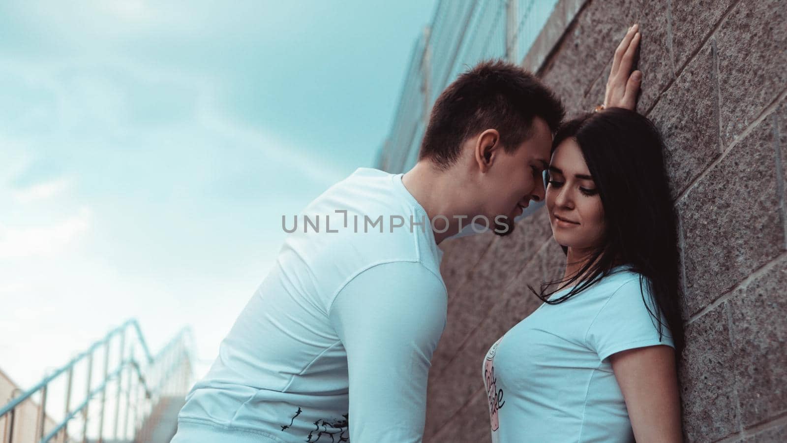 Young loving couples standing next to the brick wall, happy and satisfied by natali_brill