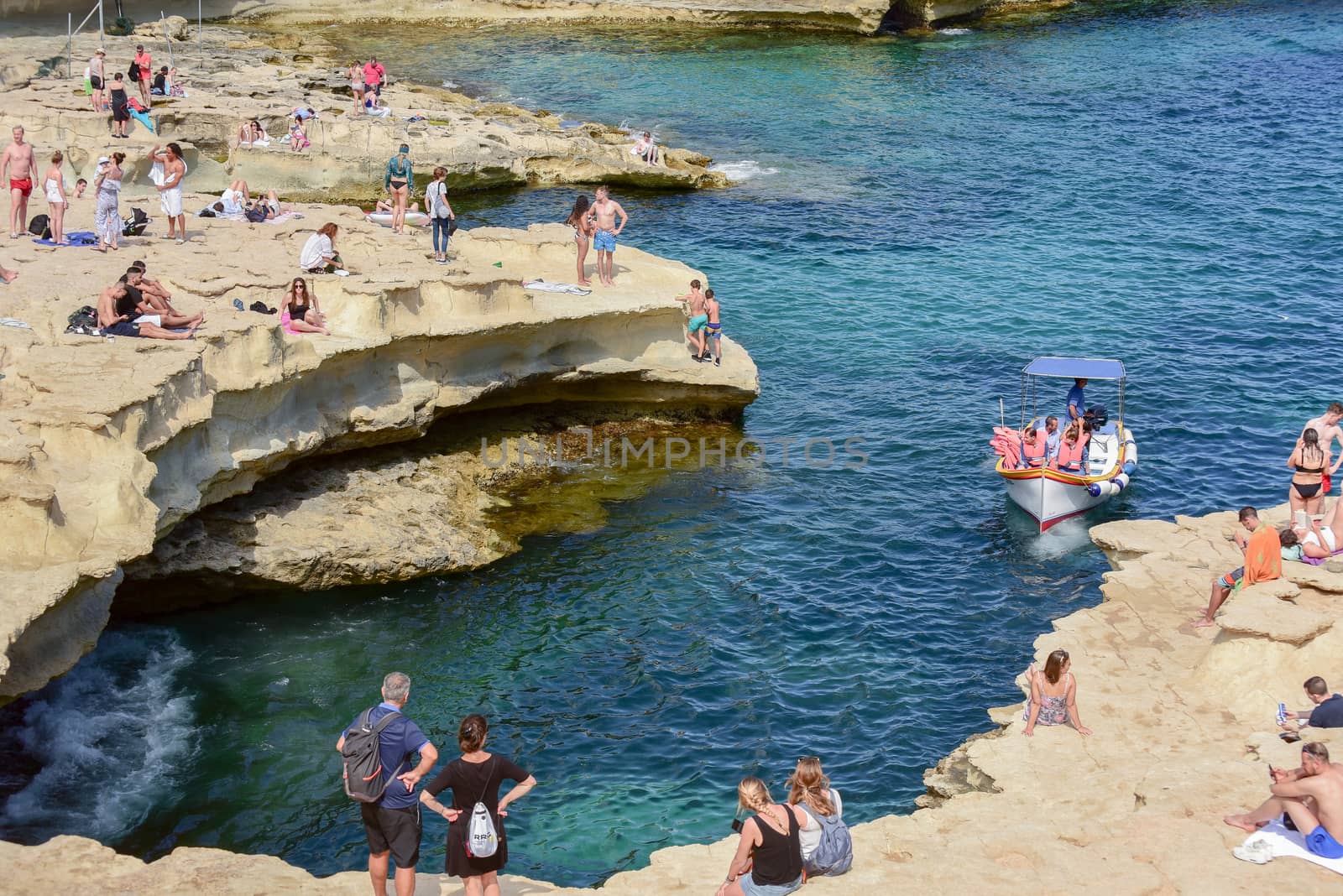 People are enjoying sunny day at Saint Peter's pool near Marsaxlokk, Malta