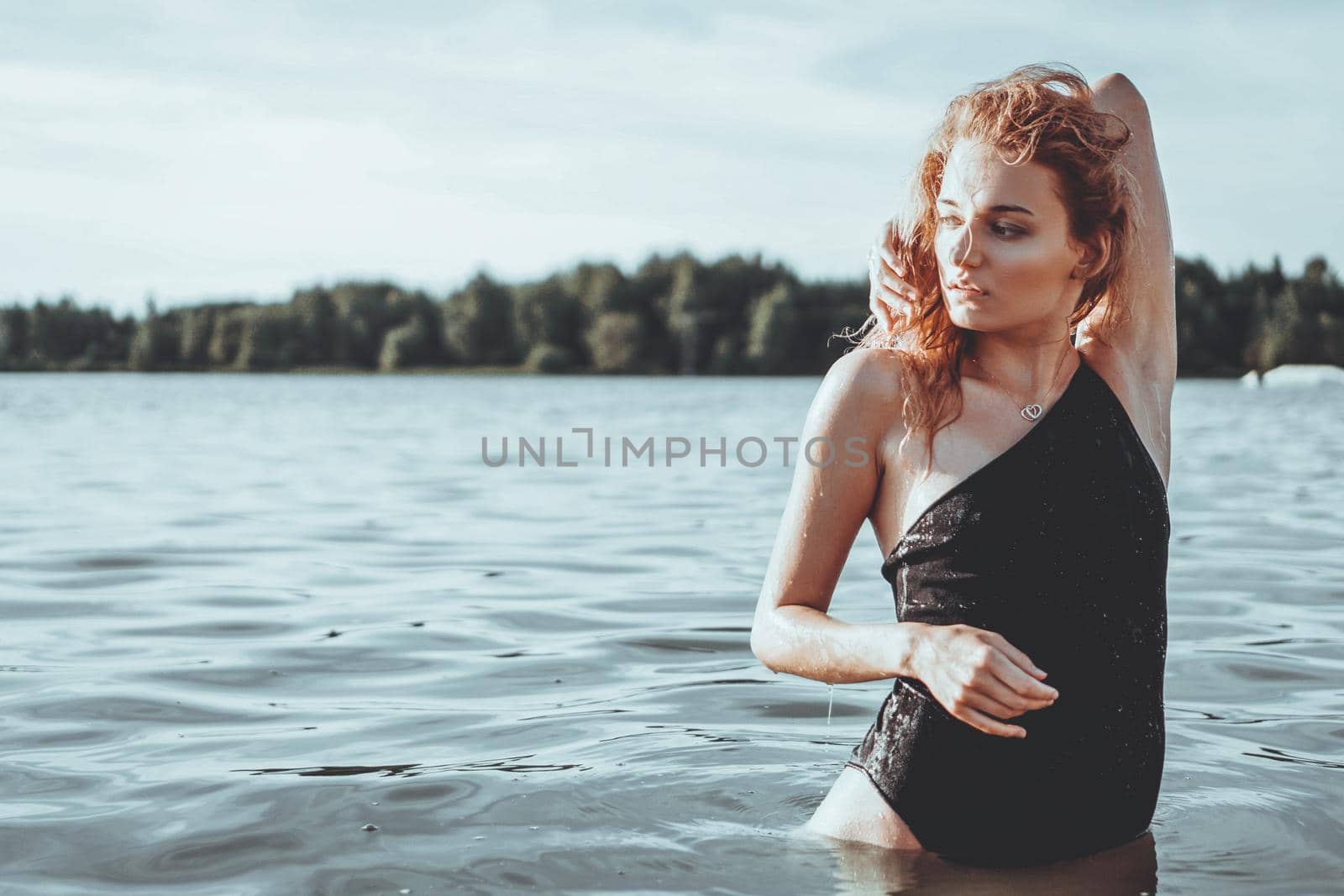 Young beautiful woman standing in the water. Black swimsuit. Vintage style