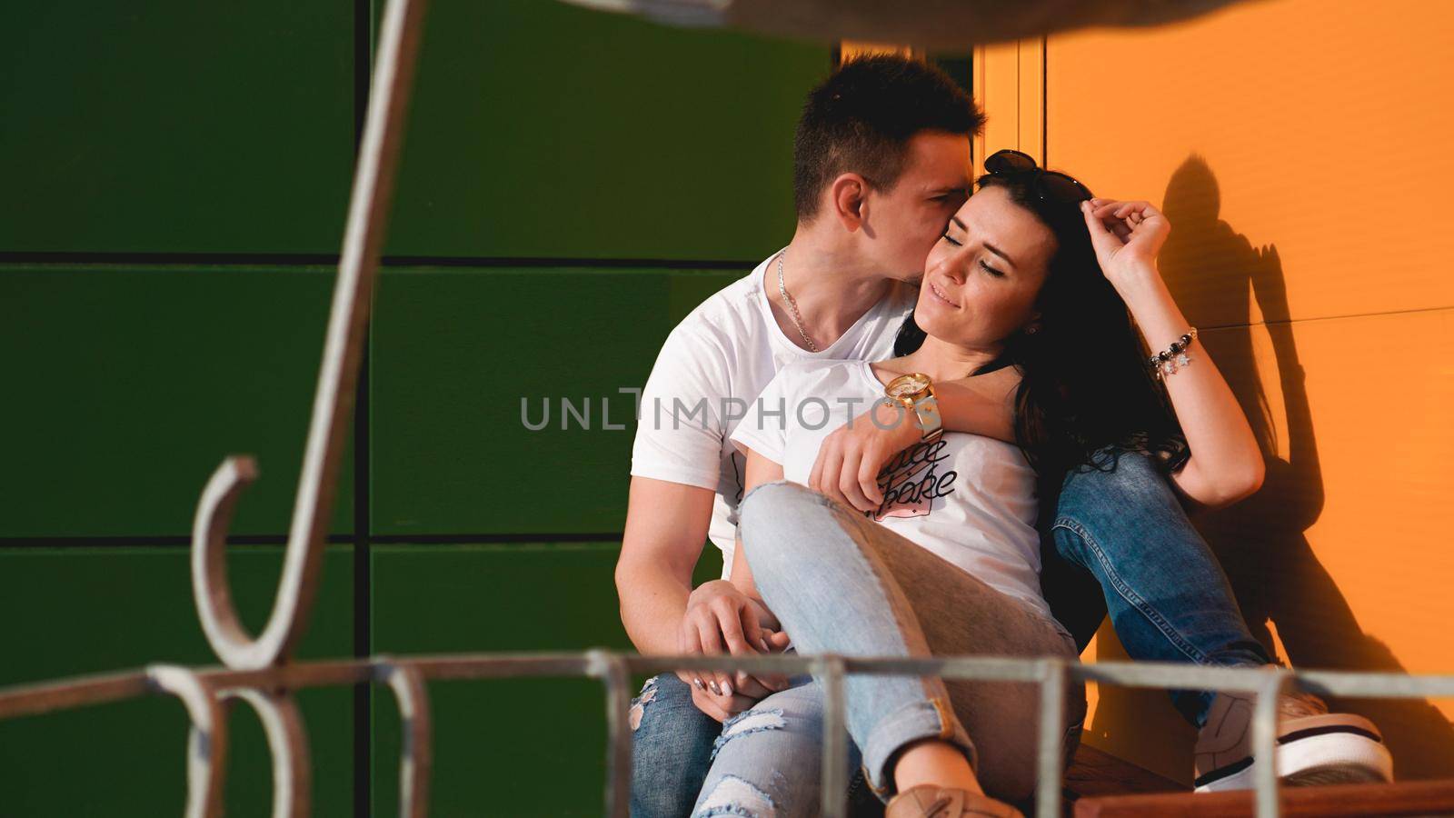 Couple kissing against isolated yellow and green wall in the city - love concept