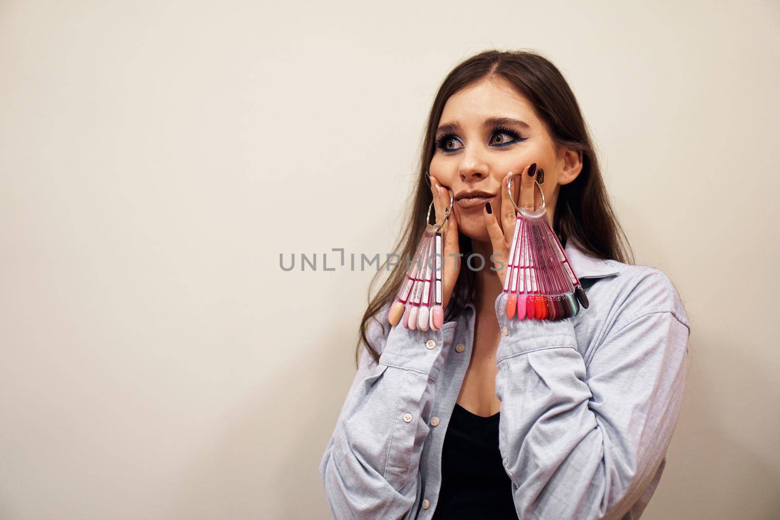 Woman holding a palette of nails. She is impressed. Comic concept - the choice of nail color for girls in a beauty salon.