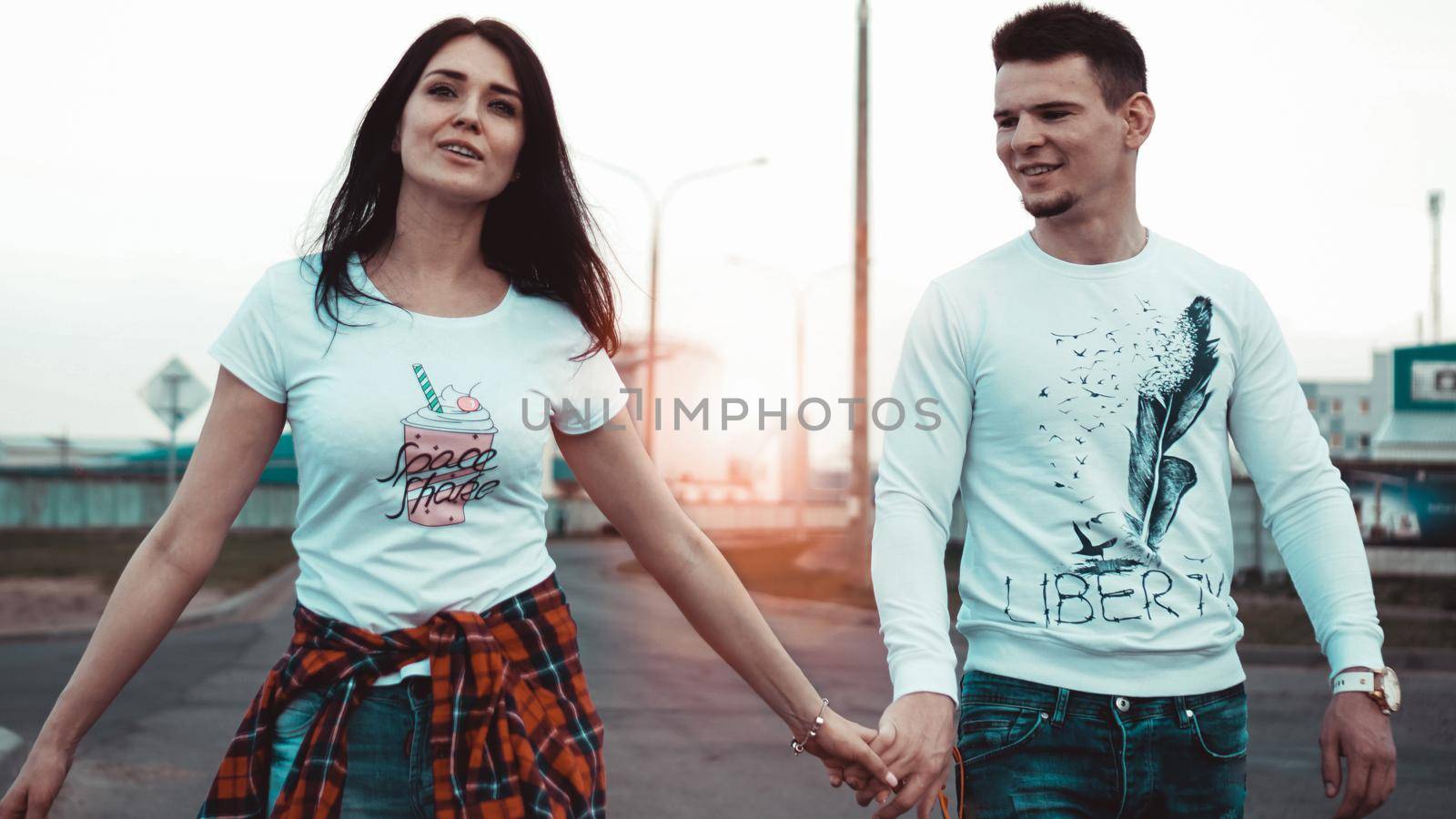 Young Couple holding hands and walking through the city street at sunset