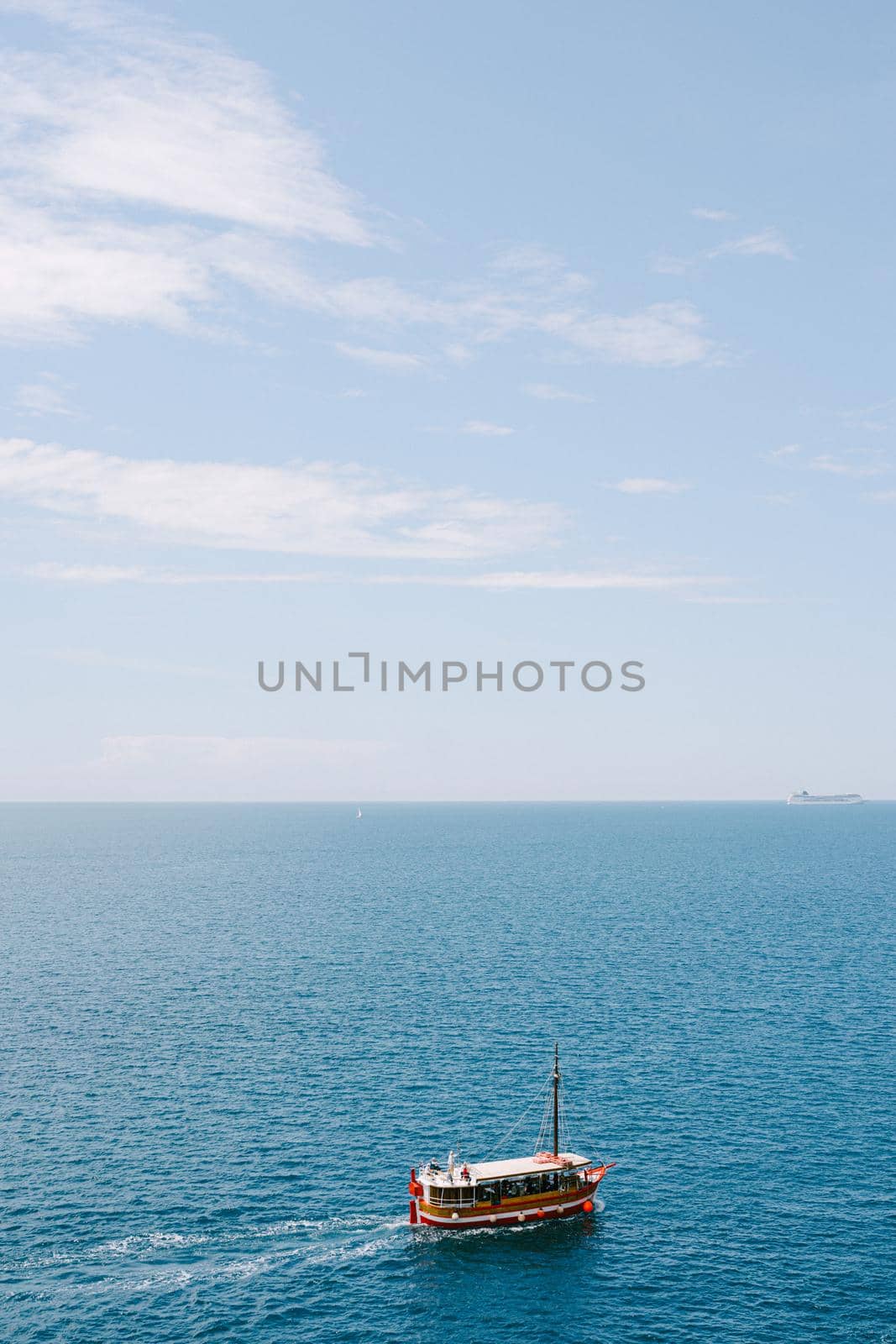 A pleasure red boat sails on the sea against the background of the sky and the horizon. Plenty of room for text. High quality photo