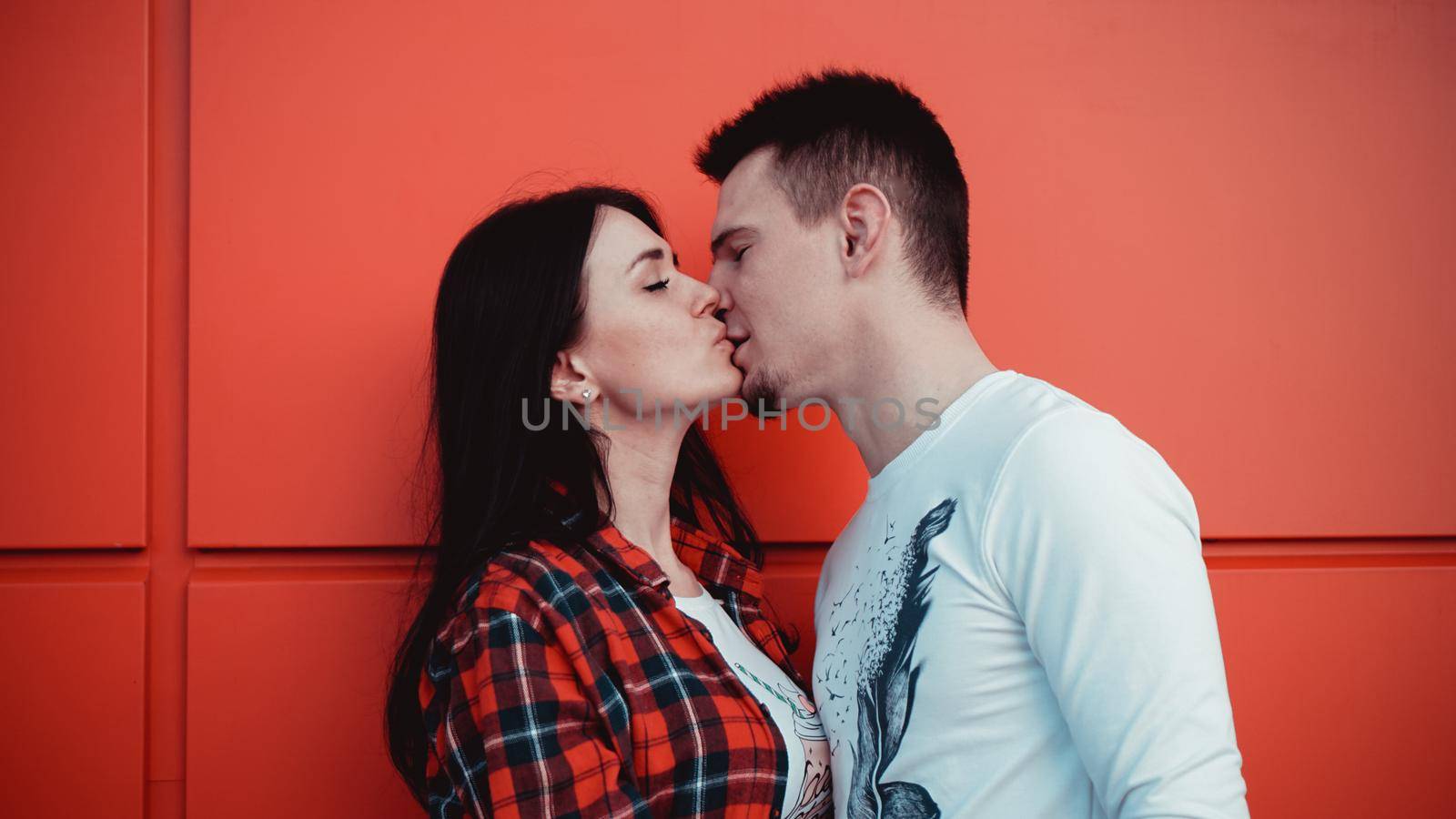 Couple kissing against isolated red wall in the city by natali_brill