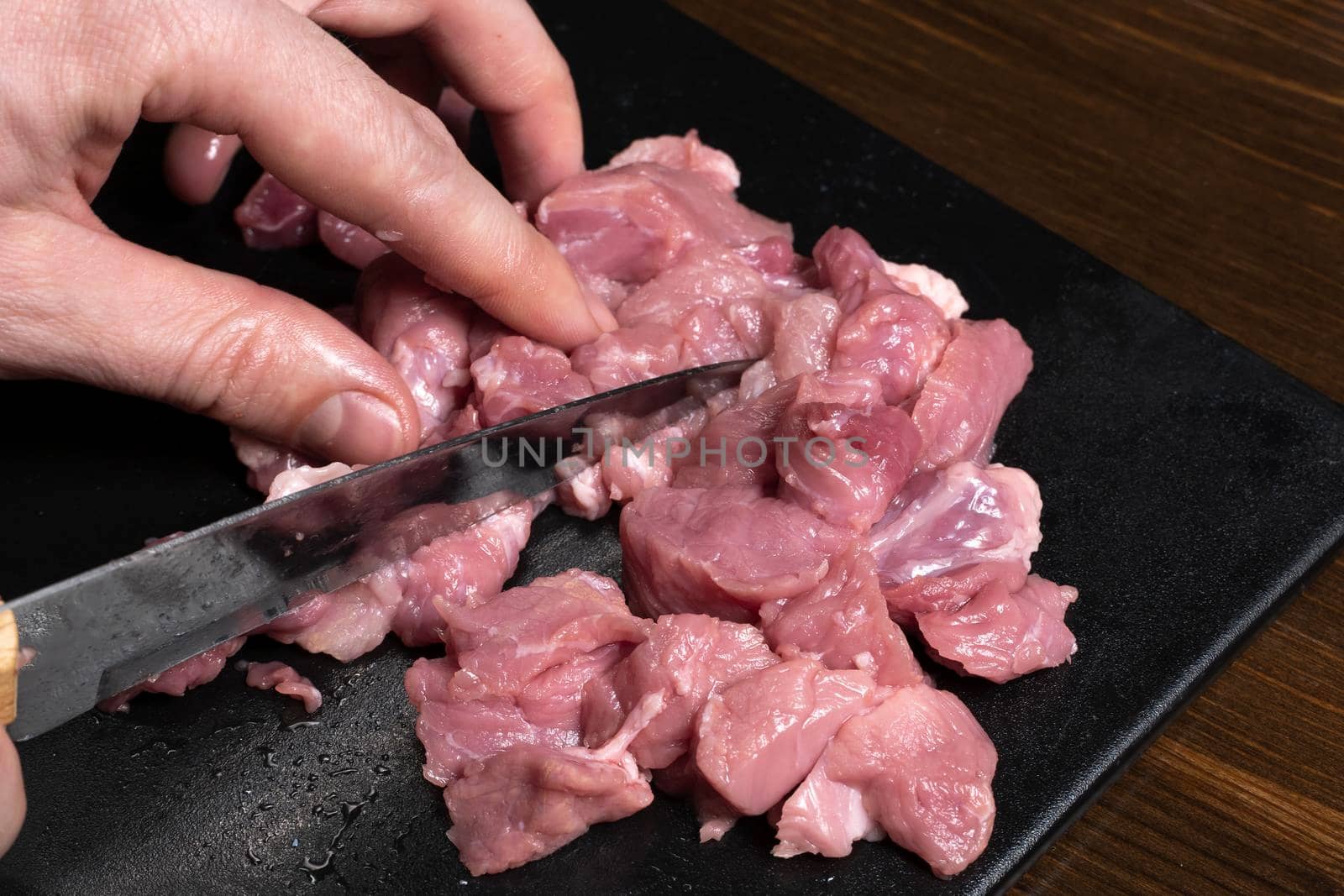 Slice the pork or beef with a knife on the table in close-up.Preparation of meat dishes and food products.Pieces of red meat for shish kebab,barbecue or kebab.Raw fresh meat is cut with a knife.recipe by YevgeniySam