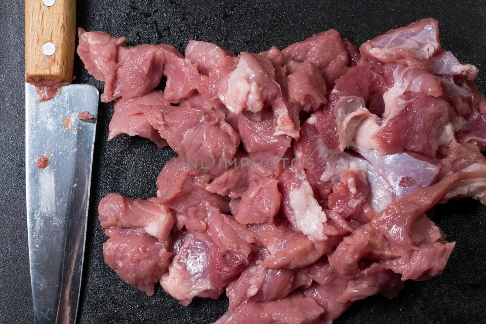Slice the pork or beef with a knife on the table in close-up.Preparation of meat dishes and food products.Pieces of red meat for shish kebab,barbecue or kebab.Raw fresh meat is cut with a knife.recipe by YevgeniySam