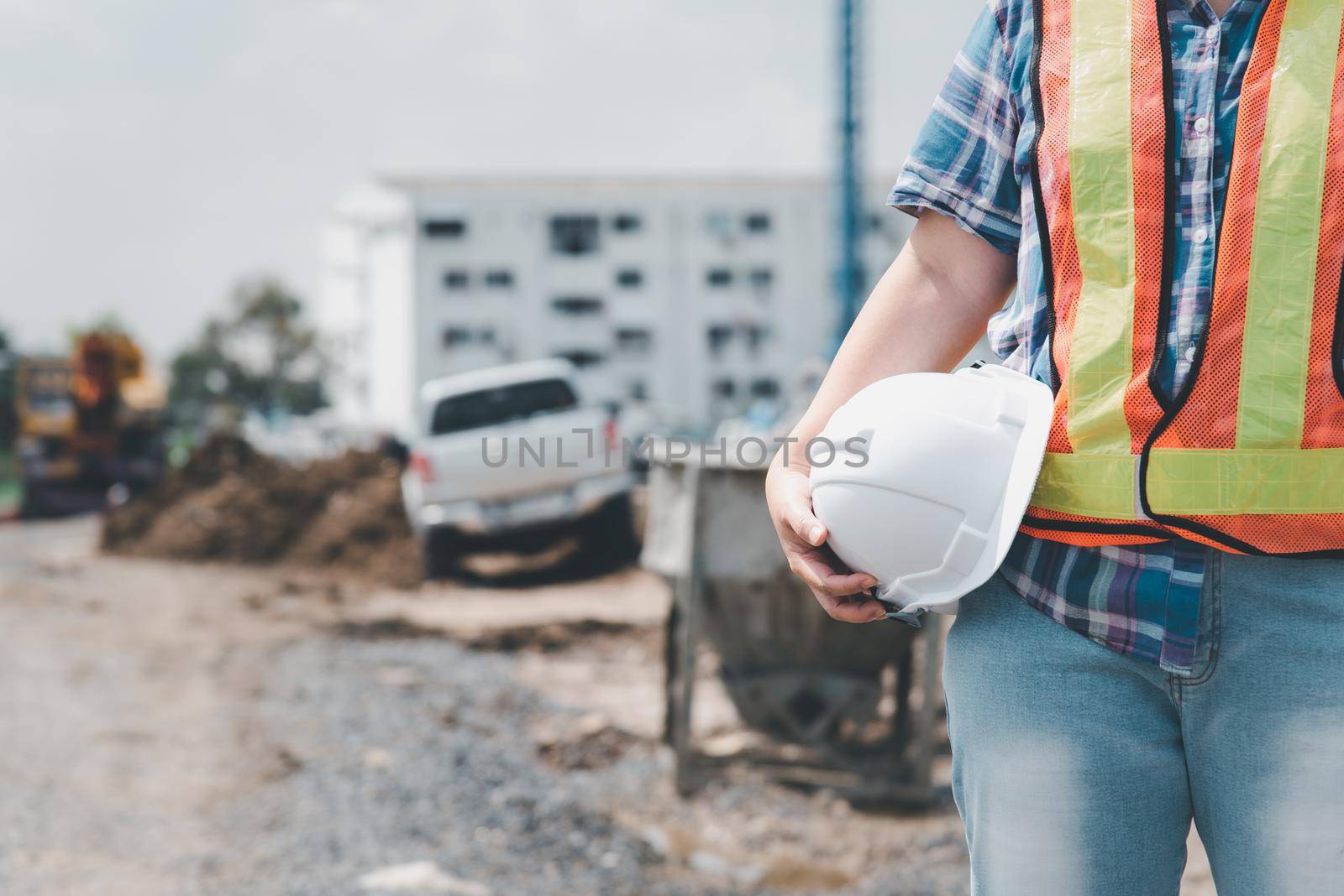 Asian woman civil construction engineer worker or architect with helmet and safety vest happy working at a building or construction site