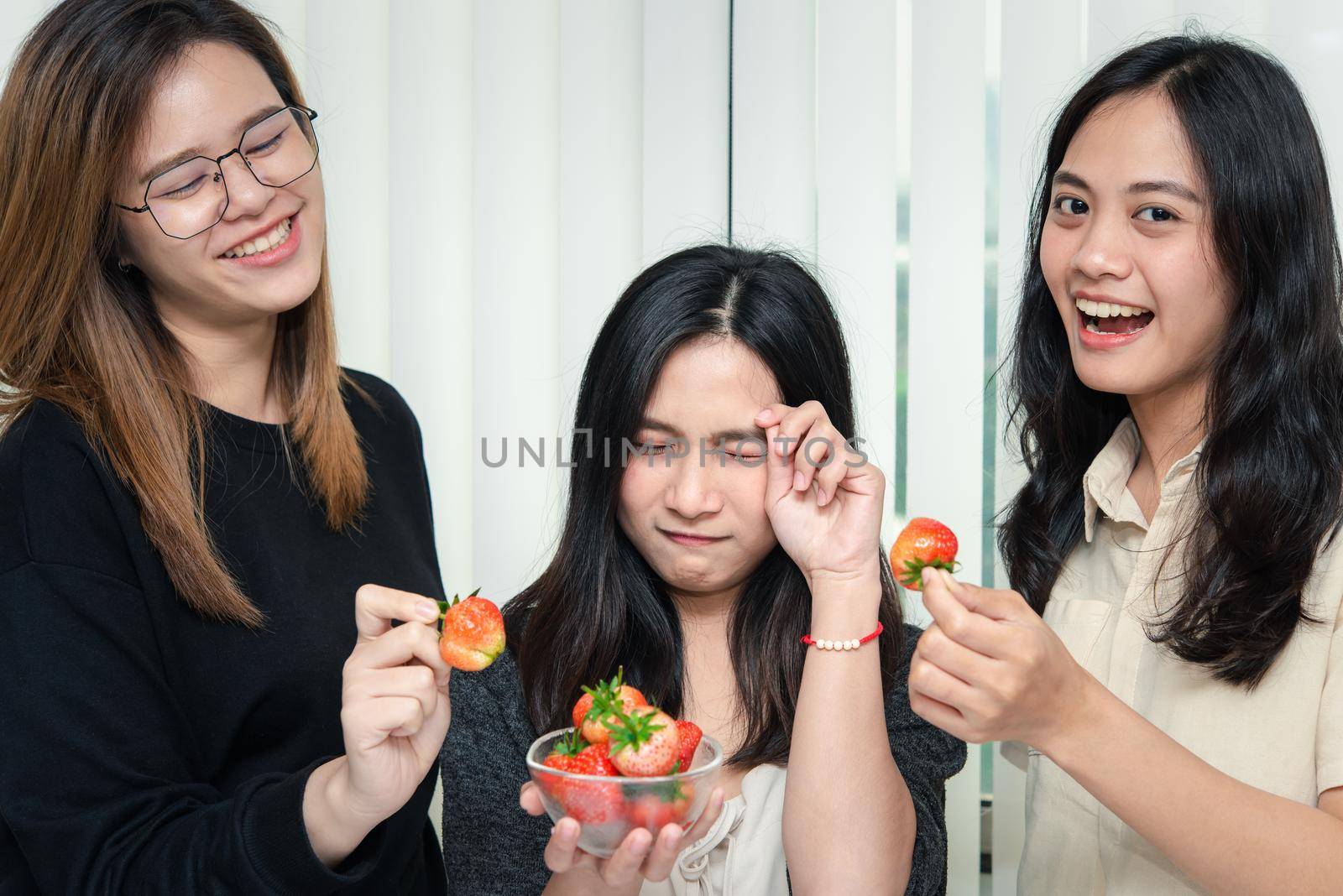 Asian pretty women holding and eating fresh strawberry is red berry fruit color and sweet juicy with enjoy and happy emotion in concept food, healthy eating in life