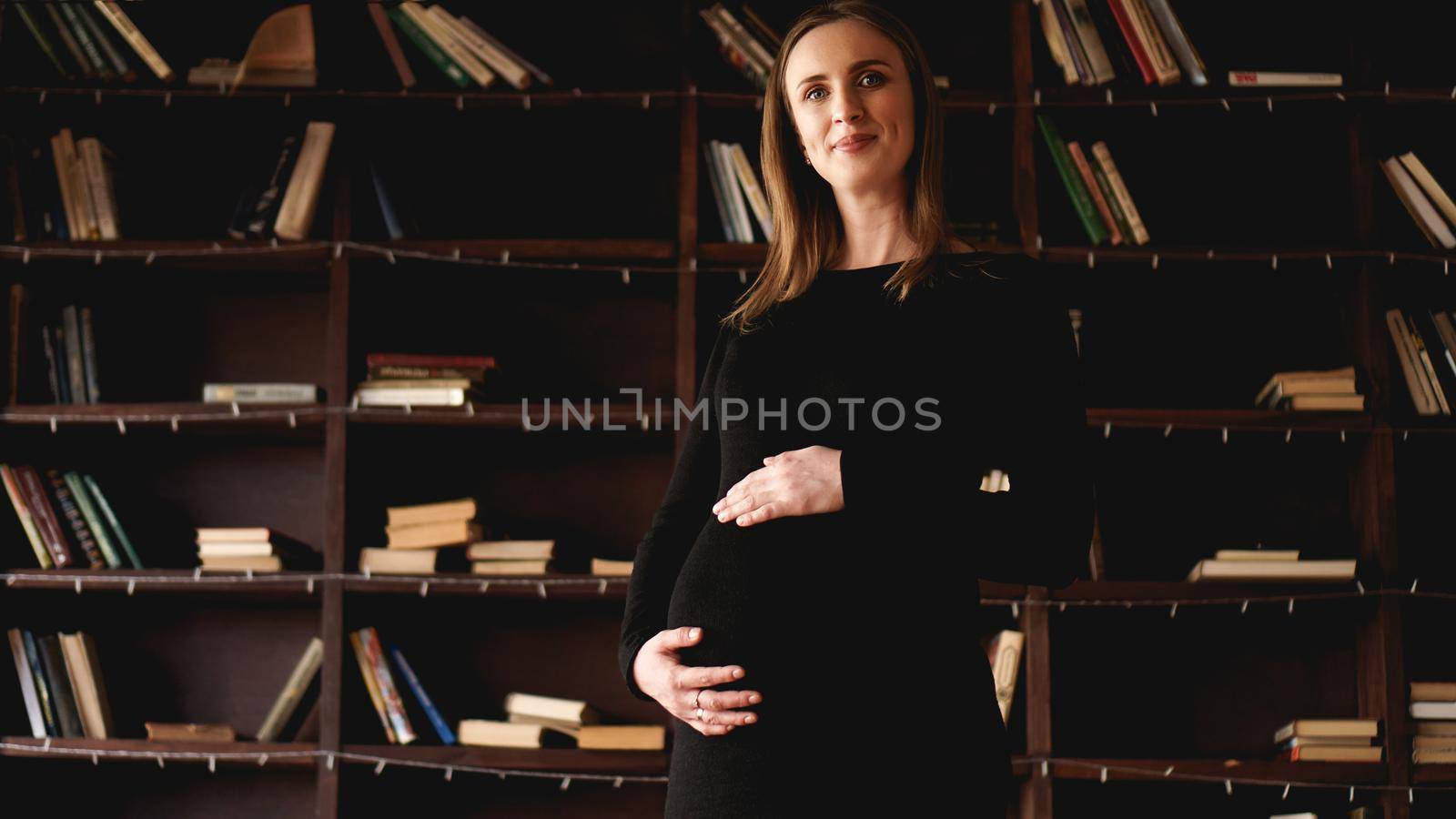 Young pretty pregnant woman in black dress in studio - loft interior