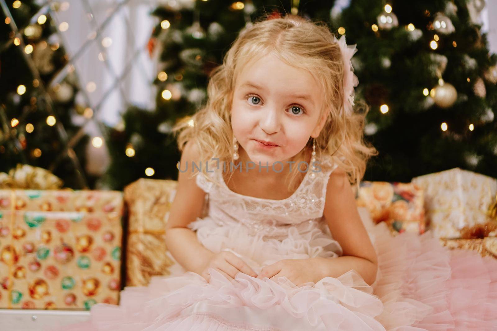 Cute little girl in pink dress with present on background Christmas tree by natali_brill