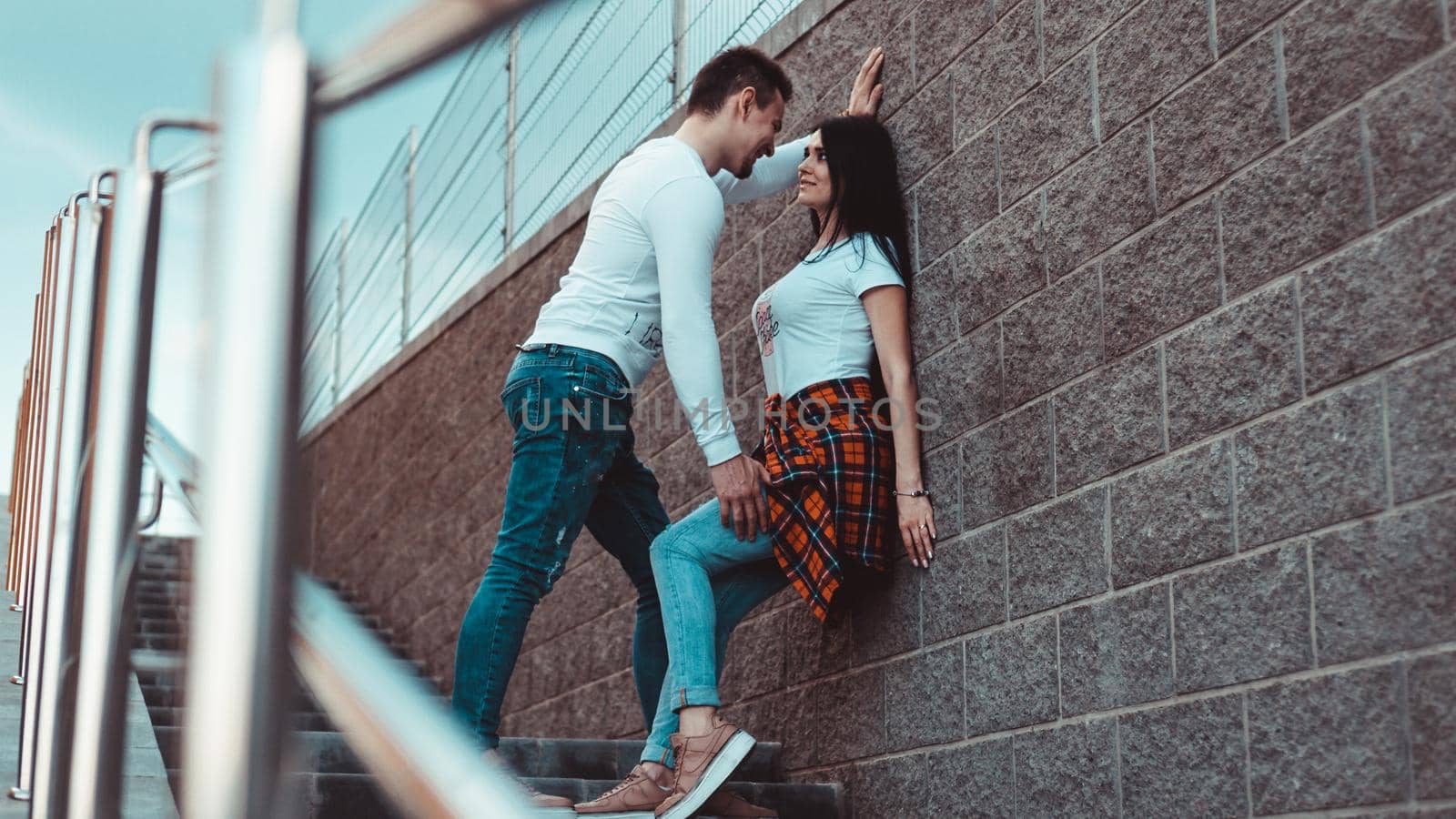 Young loving couples standing next to the brick wall, happy and satisfied by natali_brill