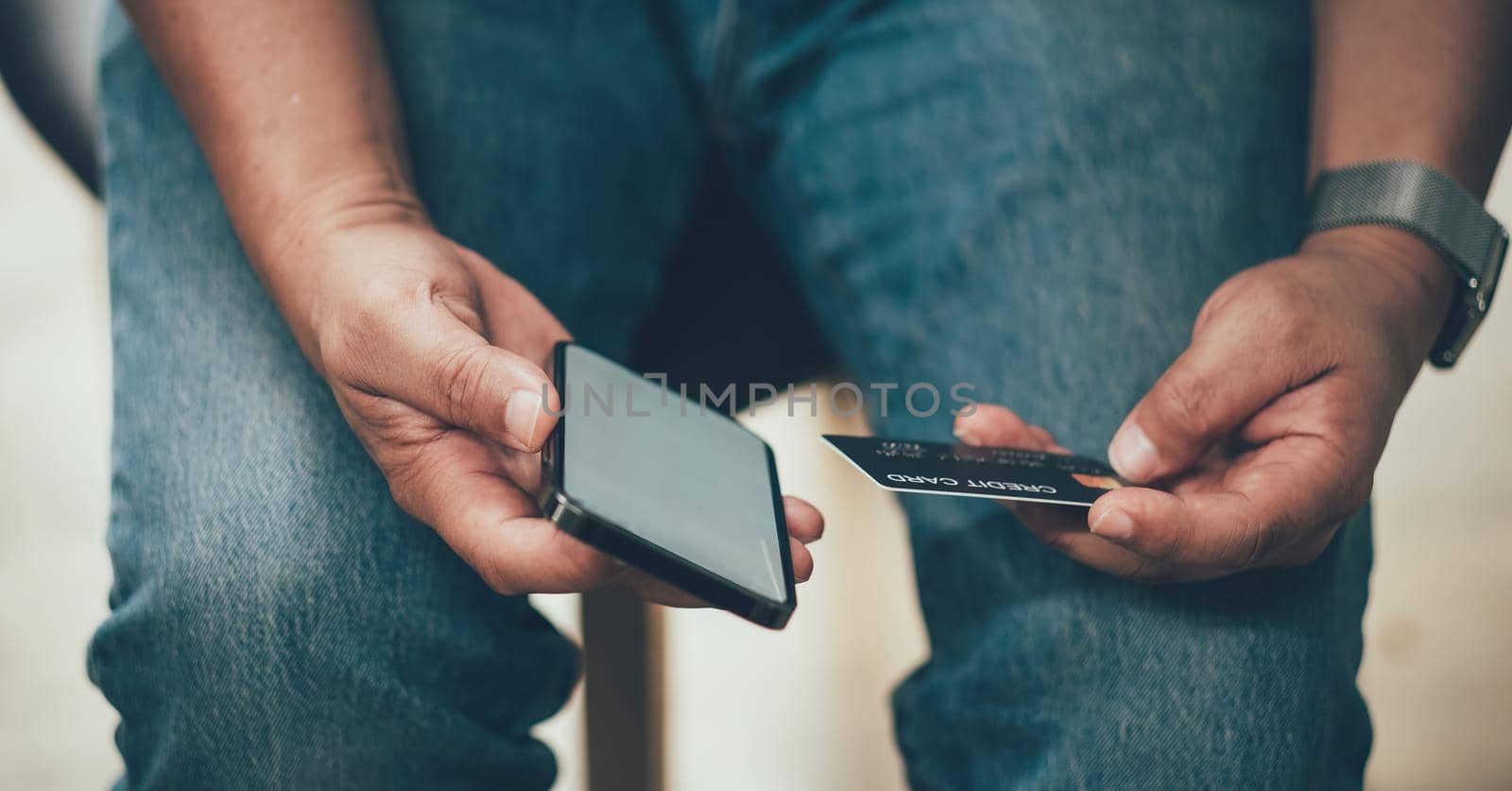 Online payment, Man's hands holding a credit card and using smart phone for online shopping at coffee cafe shop by nateemee