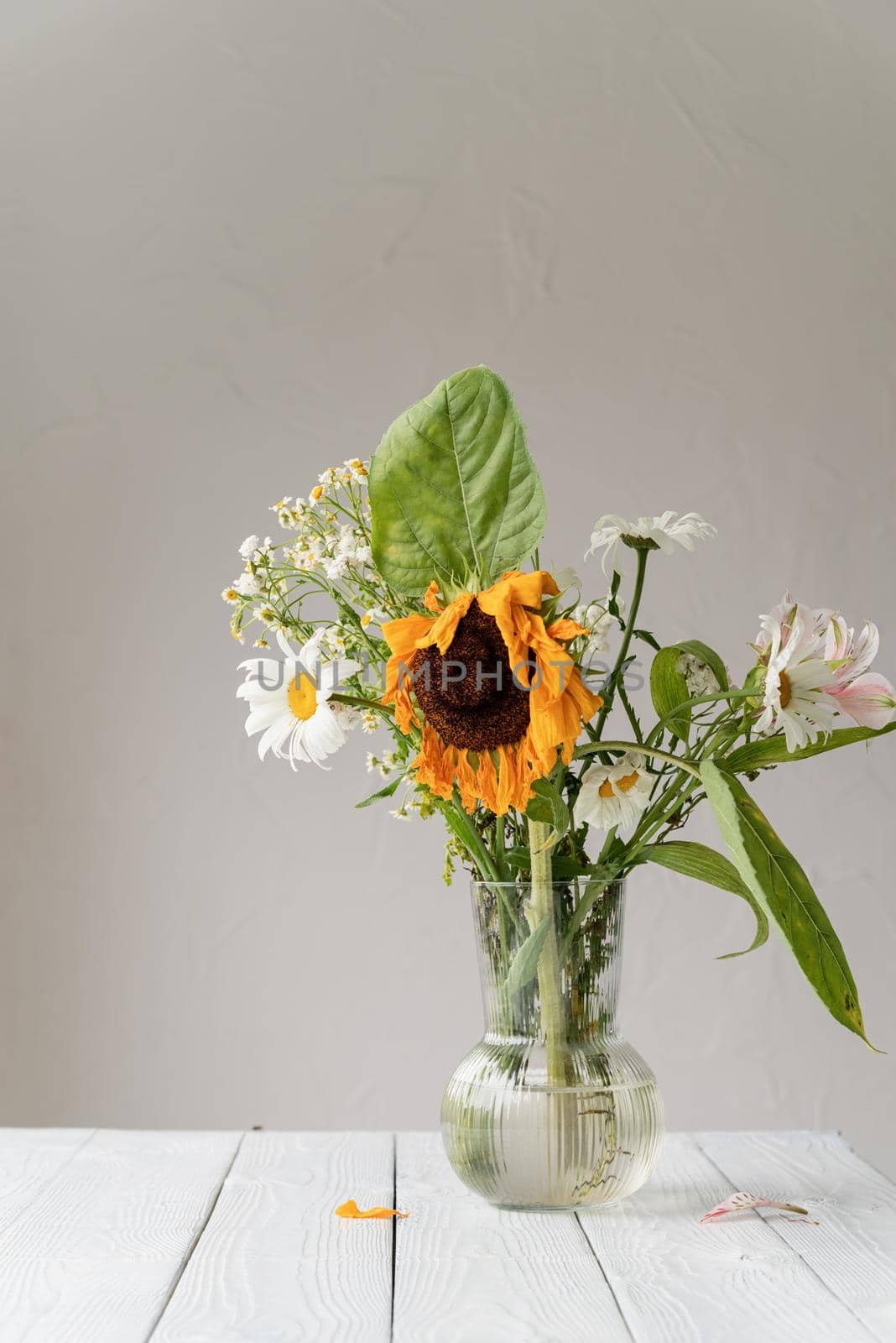 Autumn concept. A bouquet of withered dry flowers and a sunflower in a vase