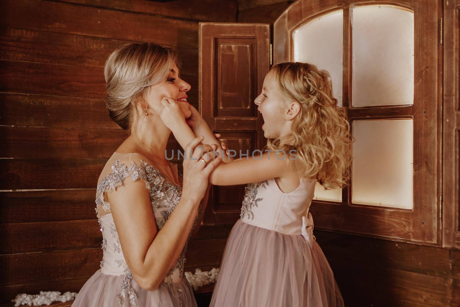 Happy Mother and her daughter in pink dresses near the Christmas decorations