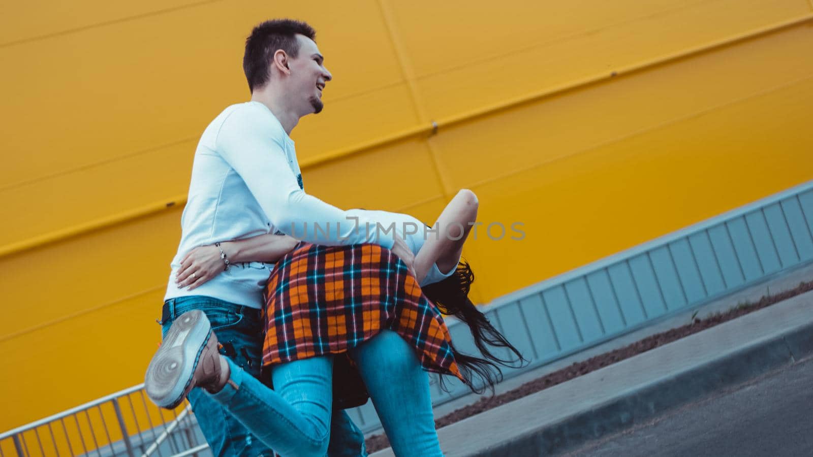 Young smiling couple in love man holding attractive woman hand, spending time together, enjoying - yellow background