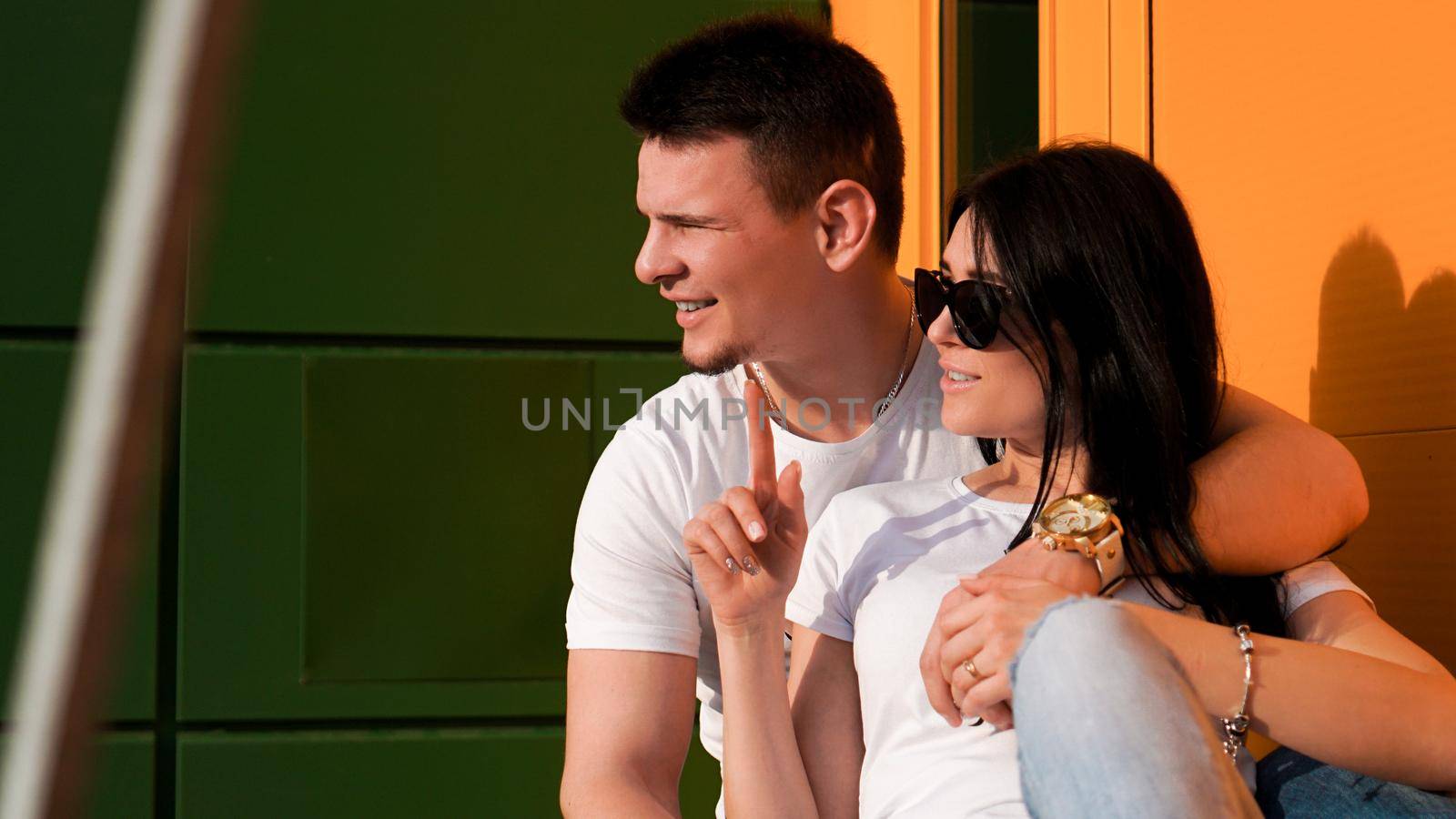 Young couple looking one way against bright wall of yellow and green. Sunny day by natali_brill