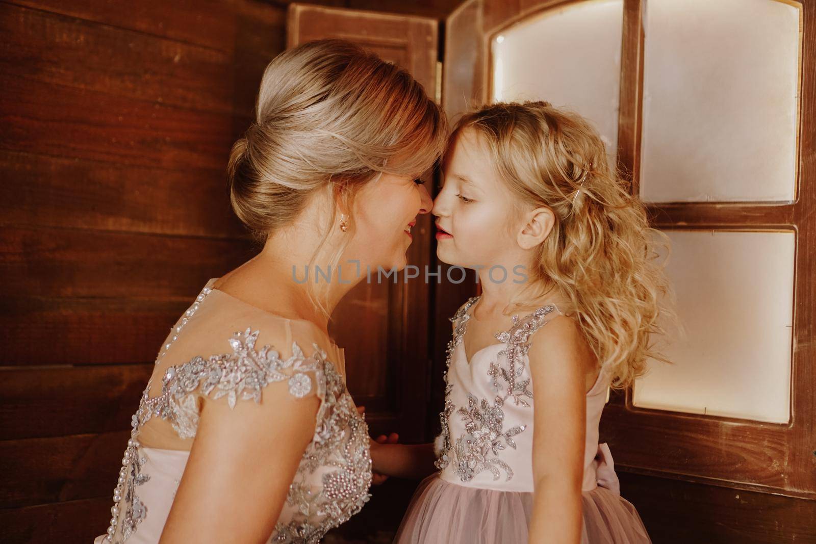 Happy Mother and her daughter in pink dresses near the Christmas decorations