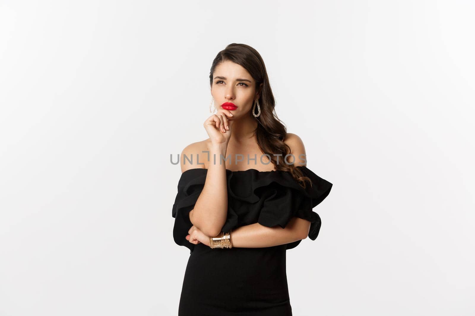 Fashion and beauty. Image of thoughtful glamour woman looking away, squinting while thinking, standing in black dress against white background by Benzoix