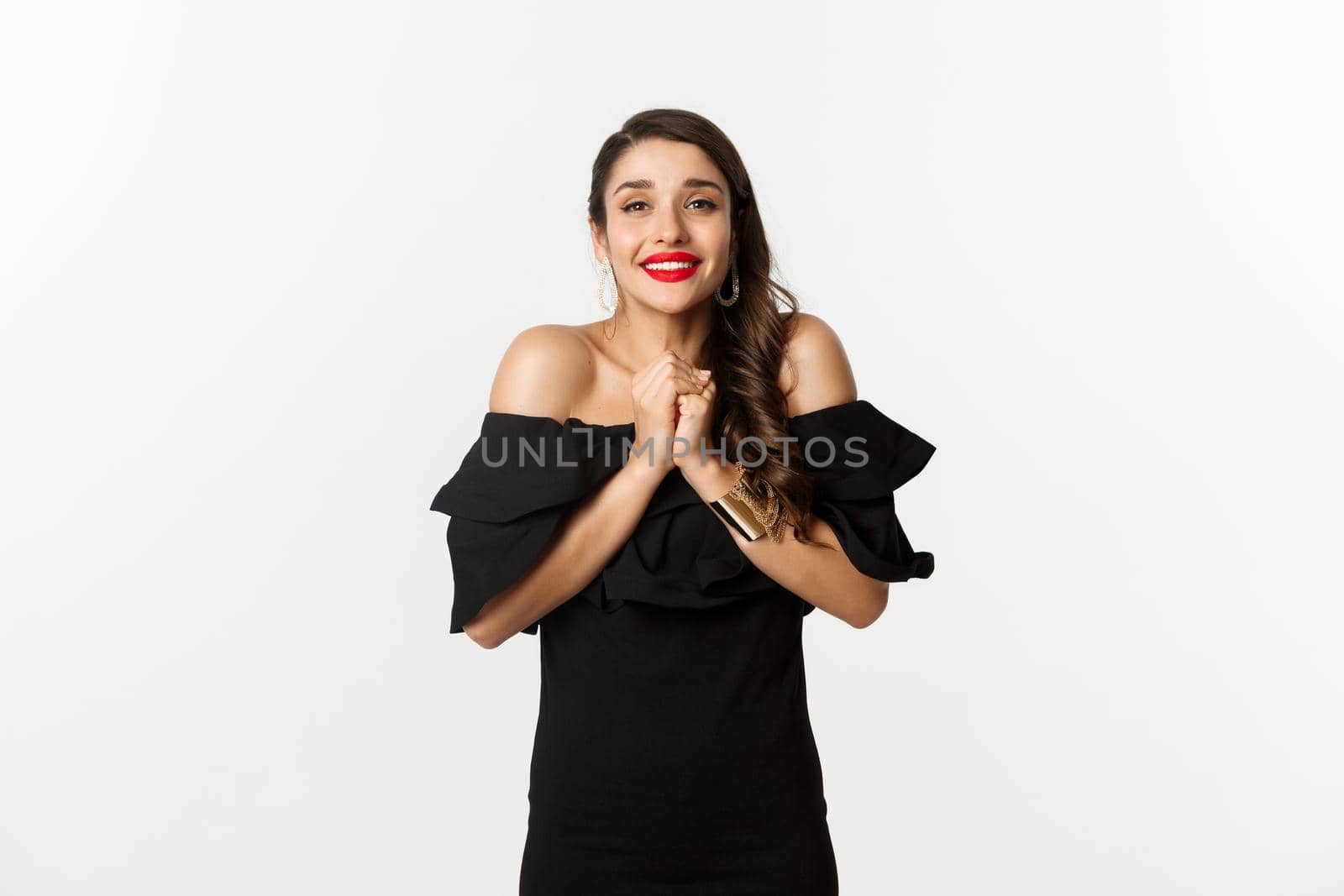Fashion and beauty. Pretty woman in black dress asking for help, showing thank you gesture, looking grateful at camera, standing over white background.