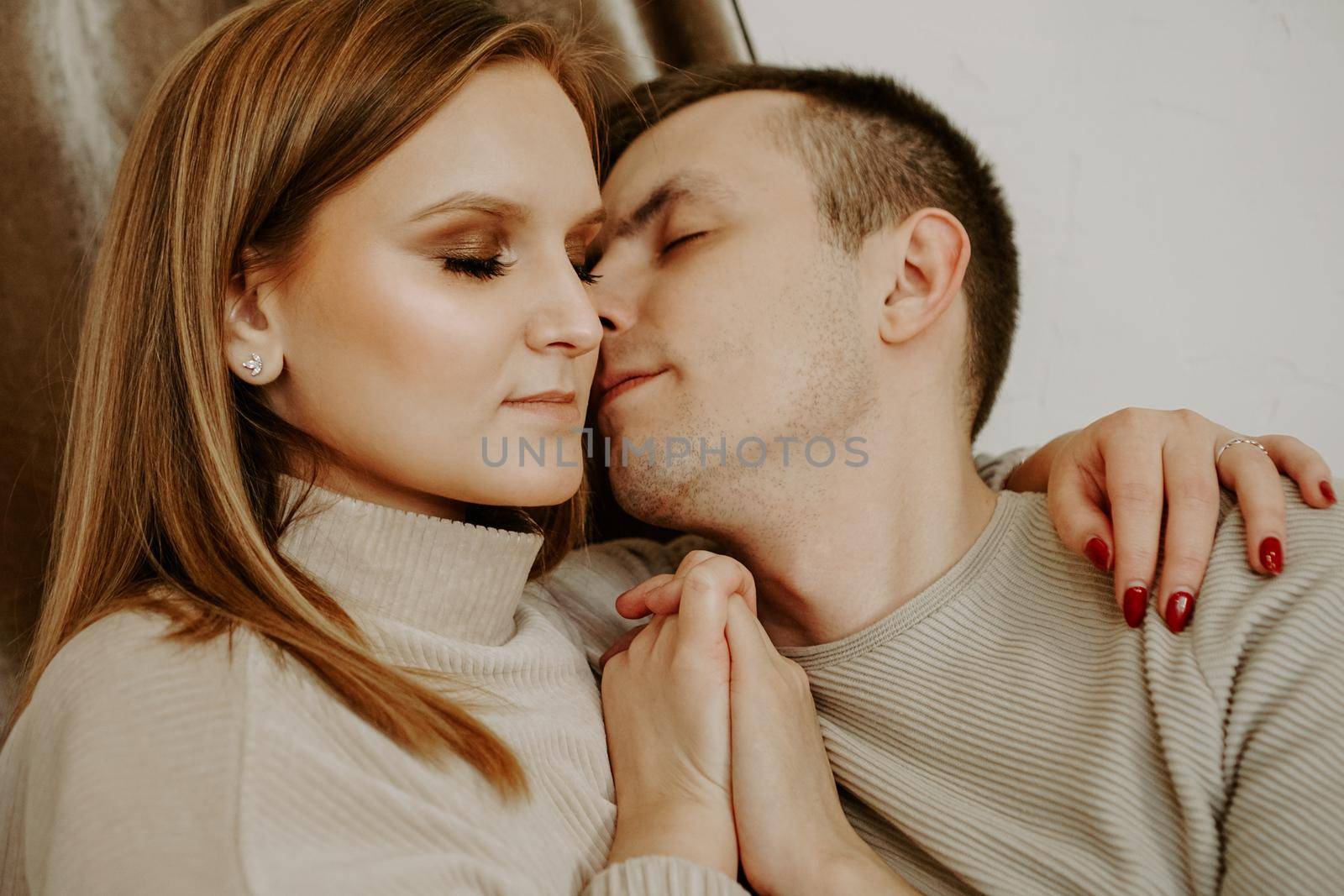 Close-up portrait of a beautiful young kissing couple in bed at home by natali_brill