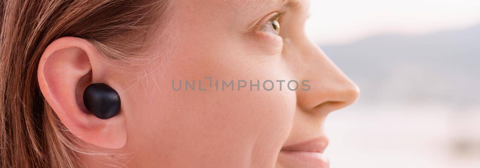 Woman using wireless earpieces, seaside on the background by Desperada